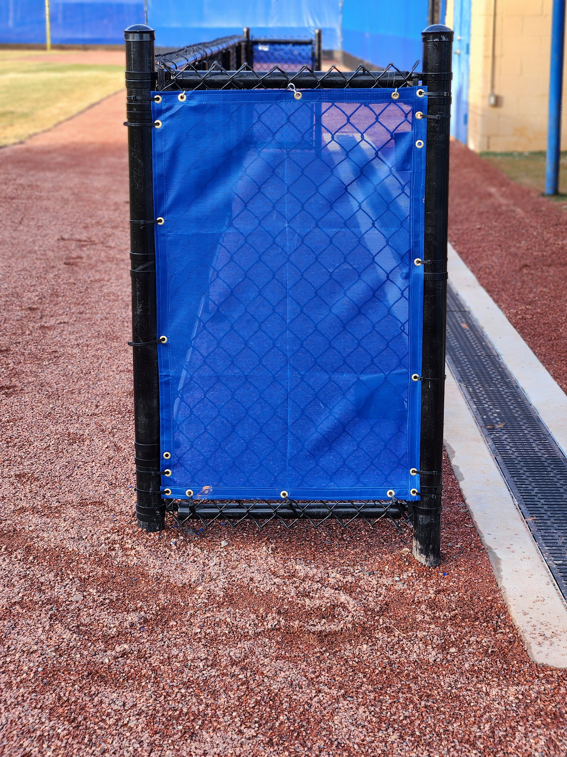 blue windscreen attached to a fence barrier surrounding a baseball dugout