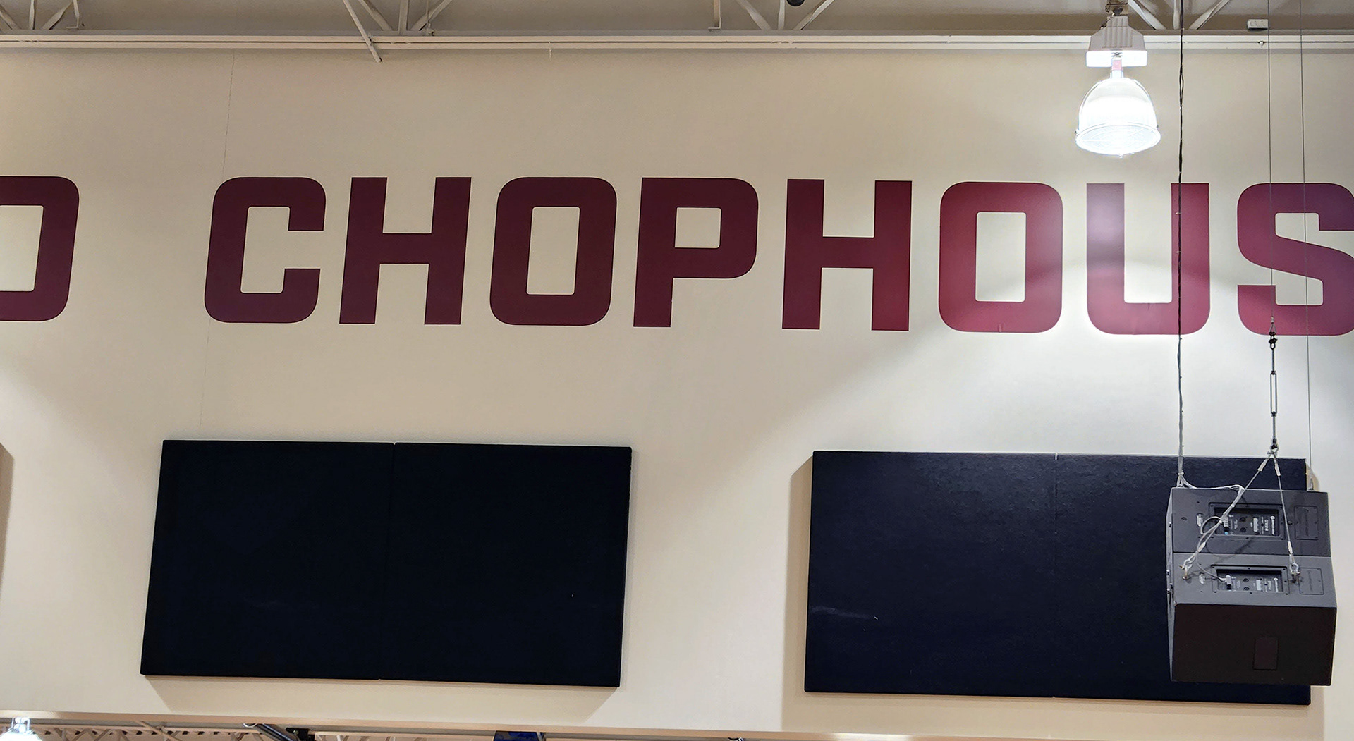 A large adhesive vinyl cutout lettering in burgundy reading 'Chophouse' displayed on the upper part of gym walls near the ceiling.
