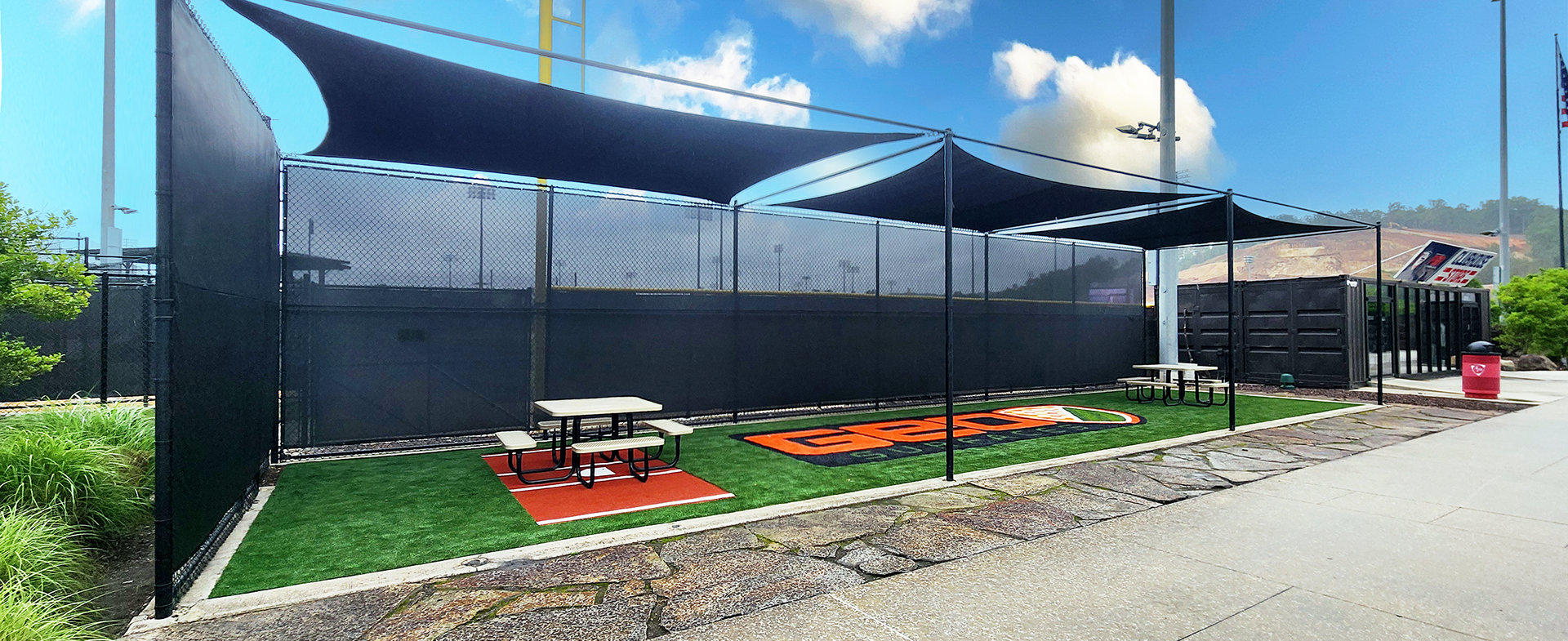 black fence windscreen and shade sails over an outdoor area. Adhesive vinyl full print concession signage