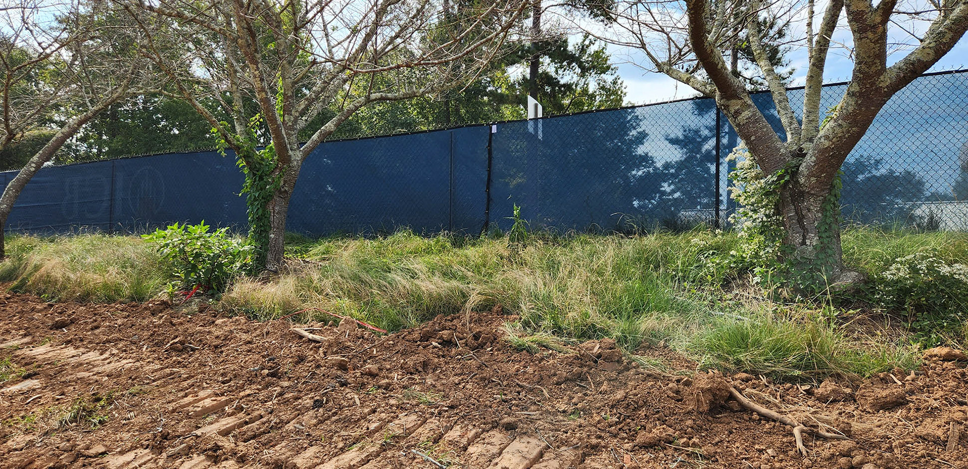A navy windscreen attached to a fence, separating outdoor areas.