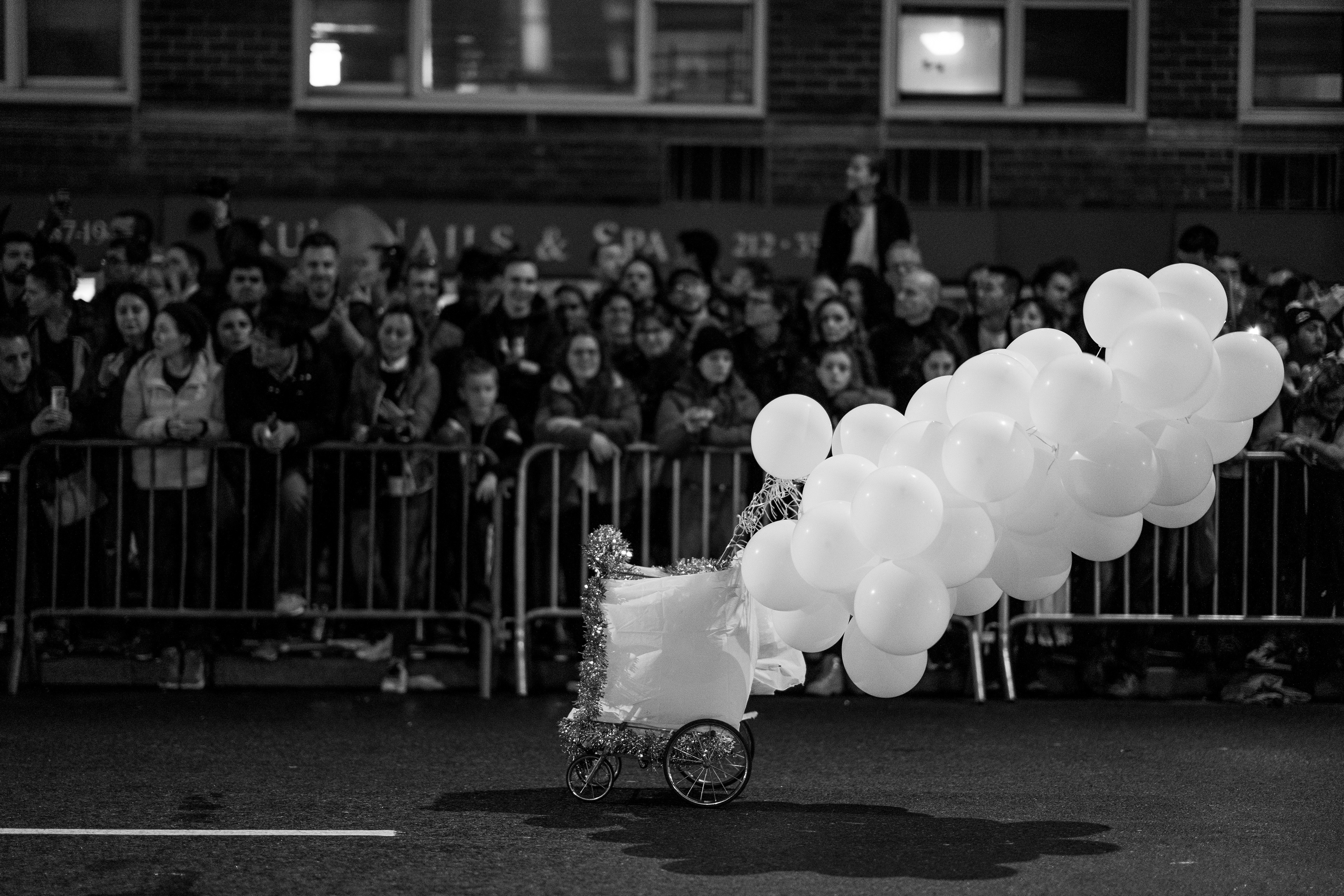 Village Halloween Parade — New York, NY. October 31st, 2019. A cart rolls down the parade with the help of dozens of helium balloons.