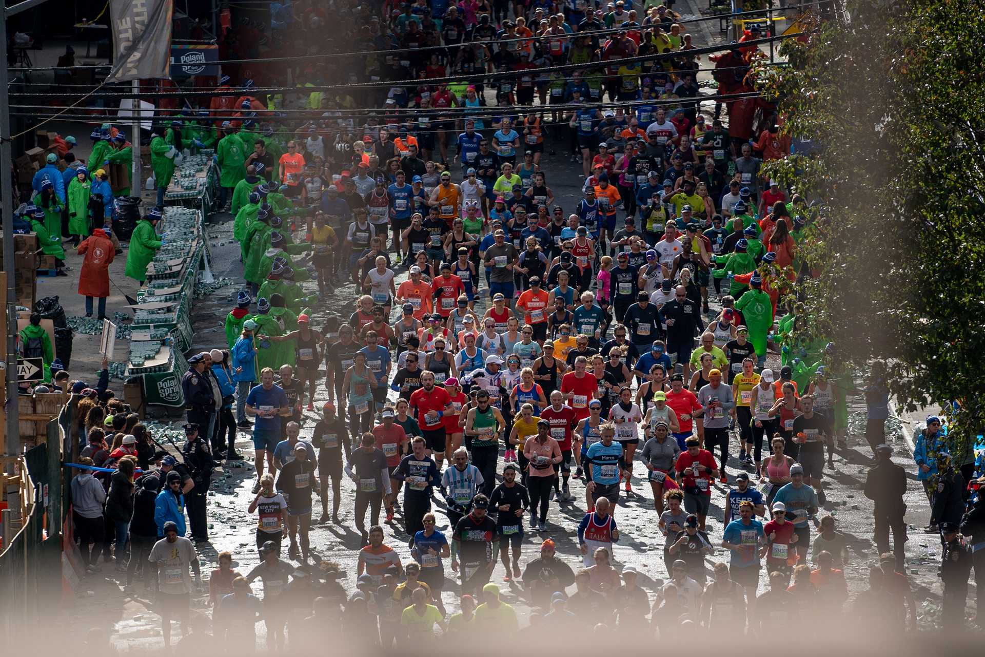 NYC Marathon — New York, NY. November 3rd, 2019. Runners on Crescent Street in Queens are given water by volunteers.