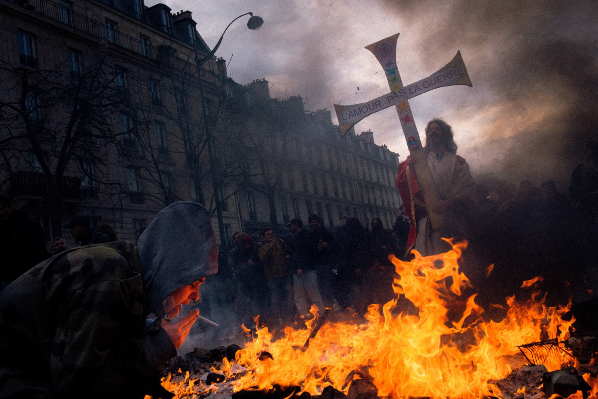 A protester lights a cigarette during a riot, Paris, 2023