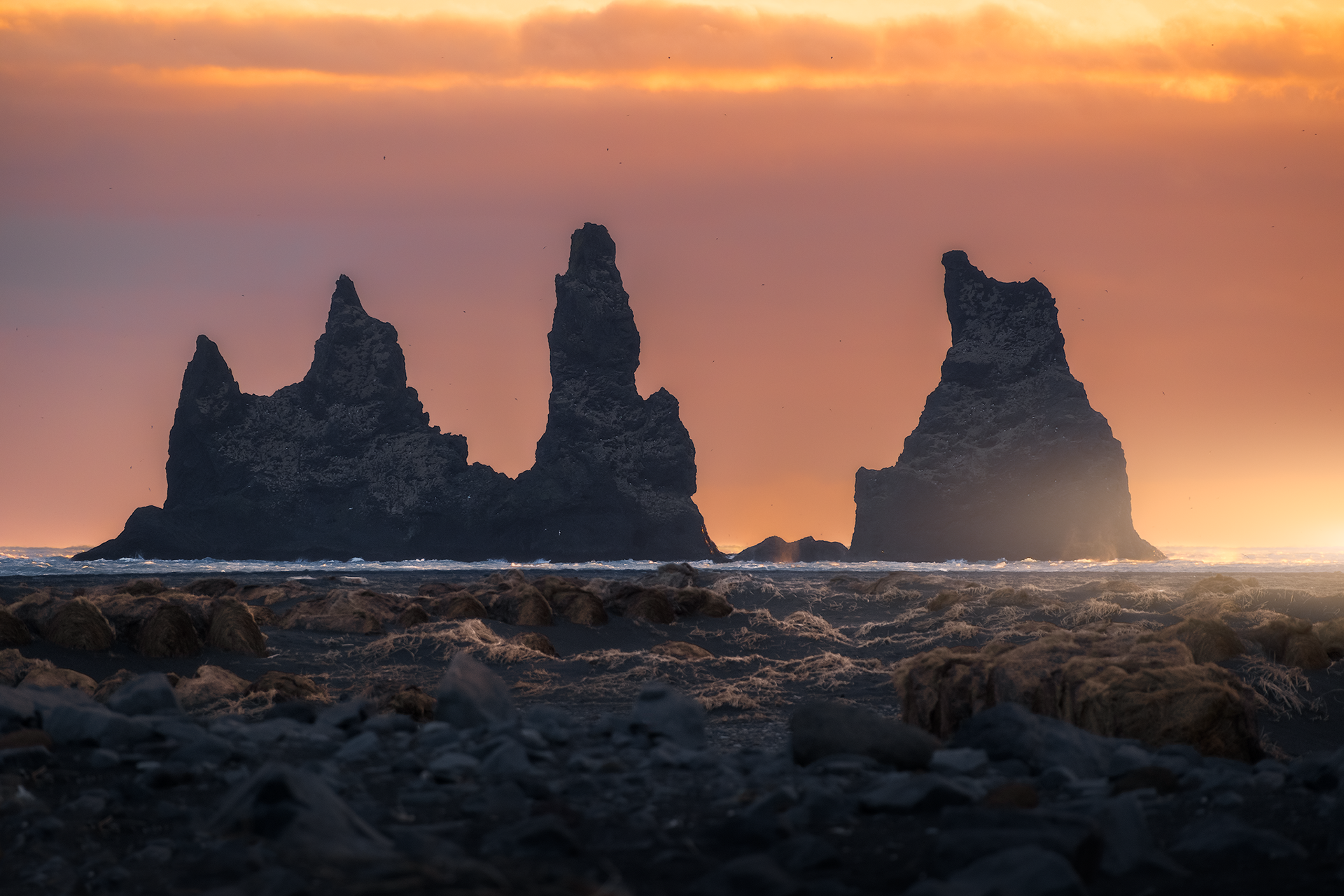 Faraglioni di Reynisdrangar al tramonto – Sagome scure dei celebri faraglioni che emergono dall’oceano, illuminate da un tramonto infuocato.