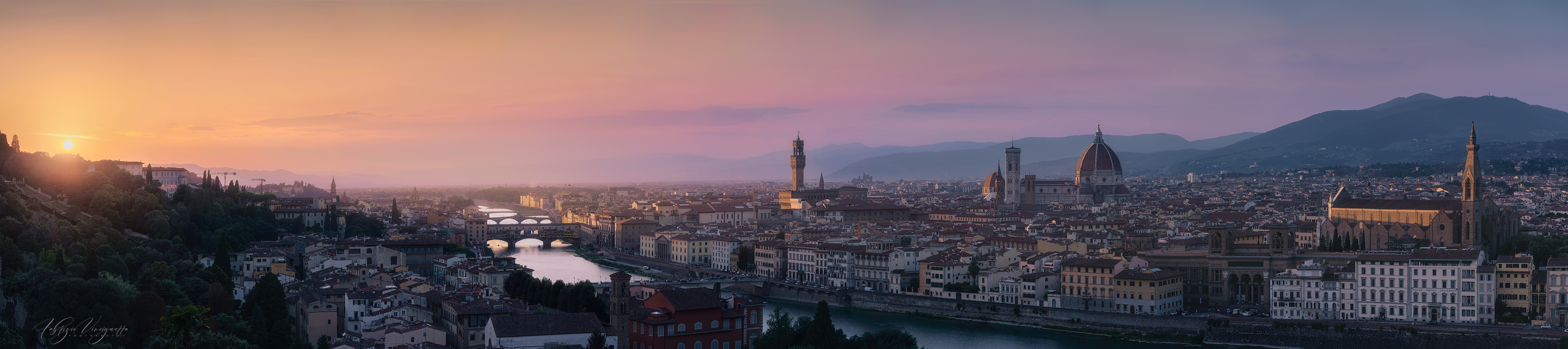 Uno spettacolare tramonto avvolge Firenze in una luce dorata, con il fiume Arno che riflette i colori caldi del cielo. Il Duomo di Santa Maria del Fiore, Palazzo Vecchio e la Basilica di Santa Croce si stagliano sull’orizzonte, offrendo una vista mozzafiato sulla città rinascimentale.