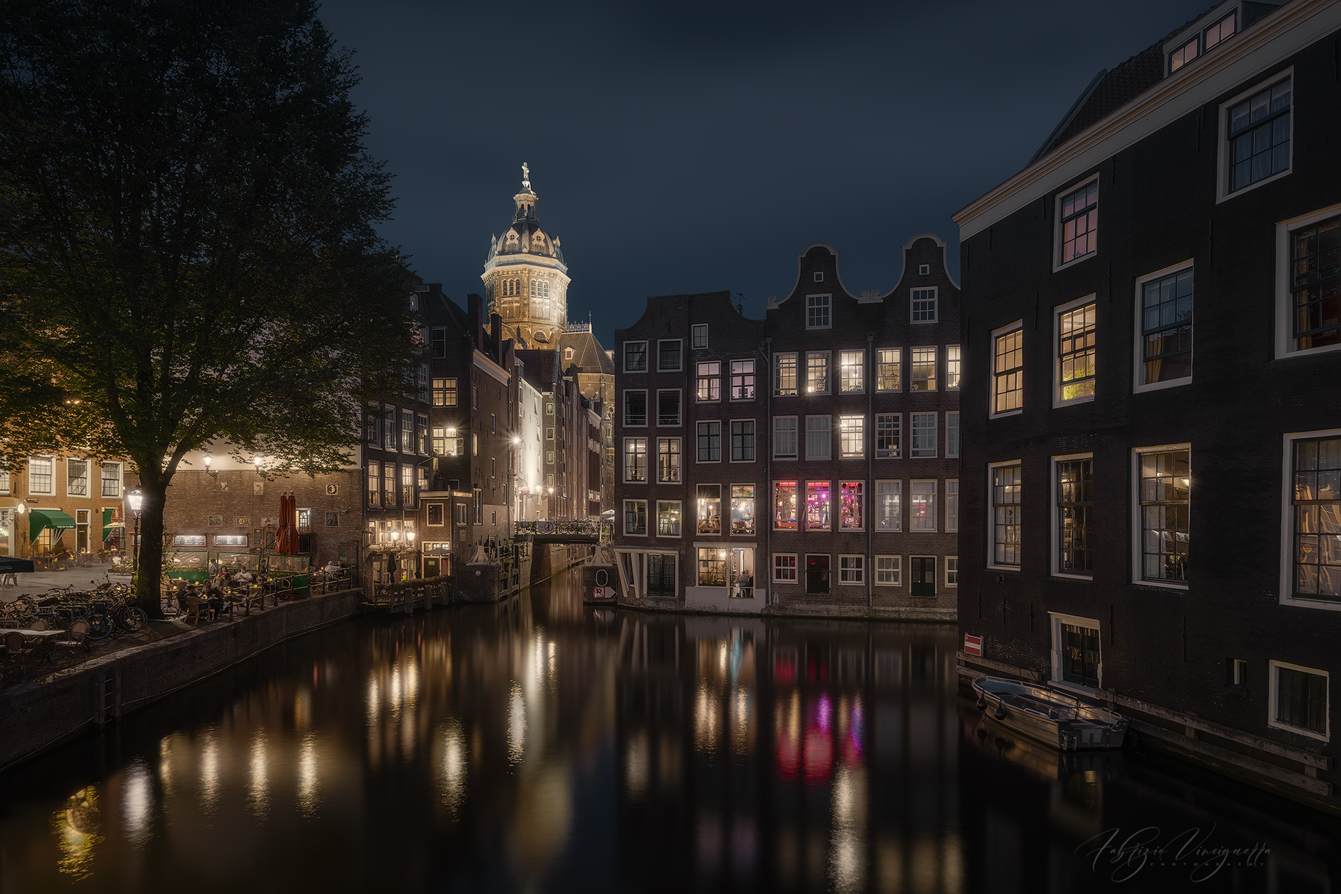 Amsterdam di notte: canale e architettura storica – Le finestre illuminate creano un contrasto affascinante con il cielo scuro, mentre l’acqua riflette le luci della città.