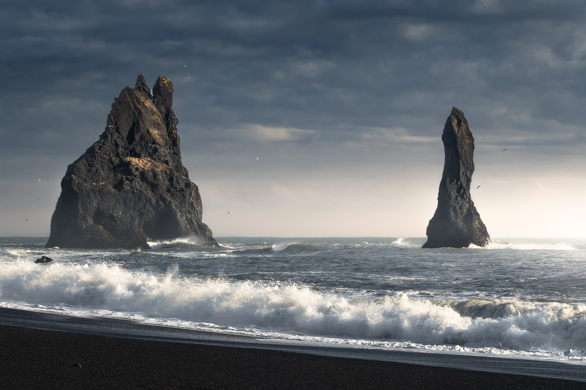 Faraglioni scolpiti dal vento – Imponenti formazioni rocciose emergono dall’oceano, con il mare agitato a rendere il paesaggio ancora più drammatico.