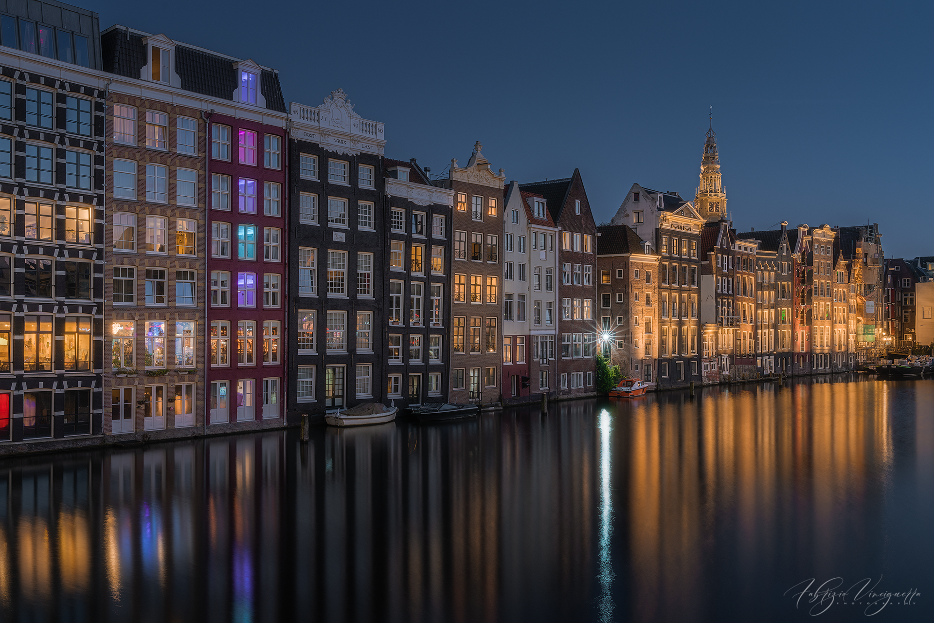 Case lungo il canale al crepuscolo – L’architettura tipica di Amsterdam si illumina nel cielo della sera, con le facciate colorate che si specchiano sull’acqua.