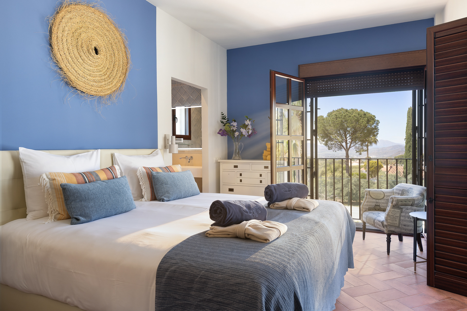 Bright B&B bedroom with balcony and countryside views in Andalusia, styled for a relaxing guest stay.