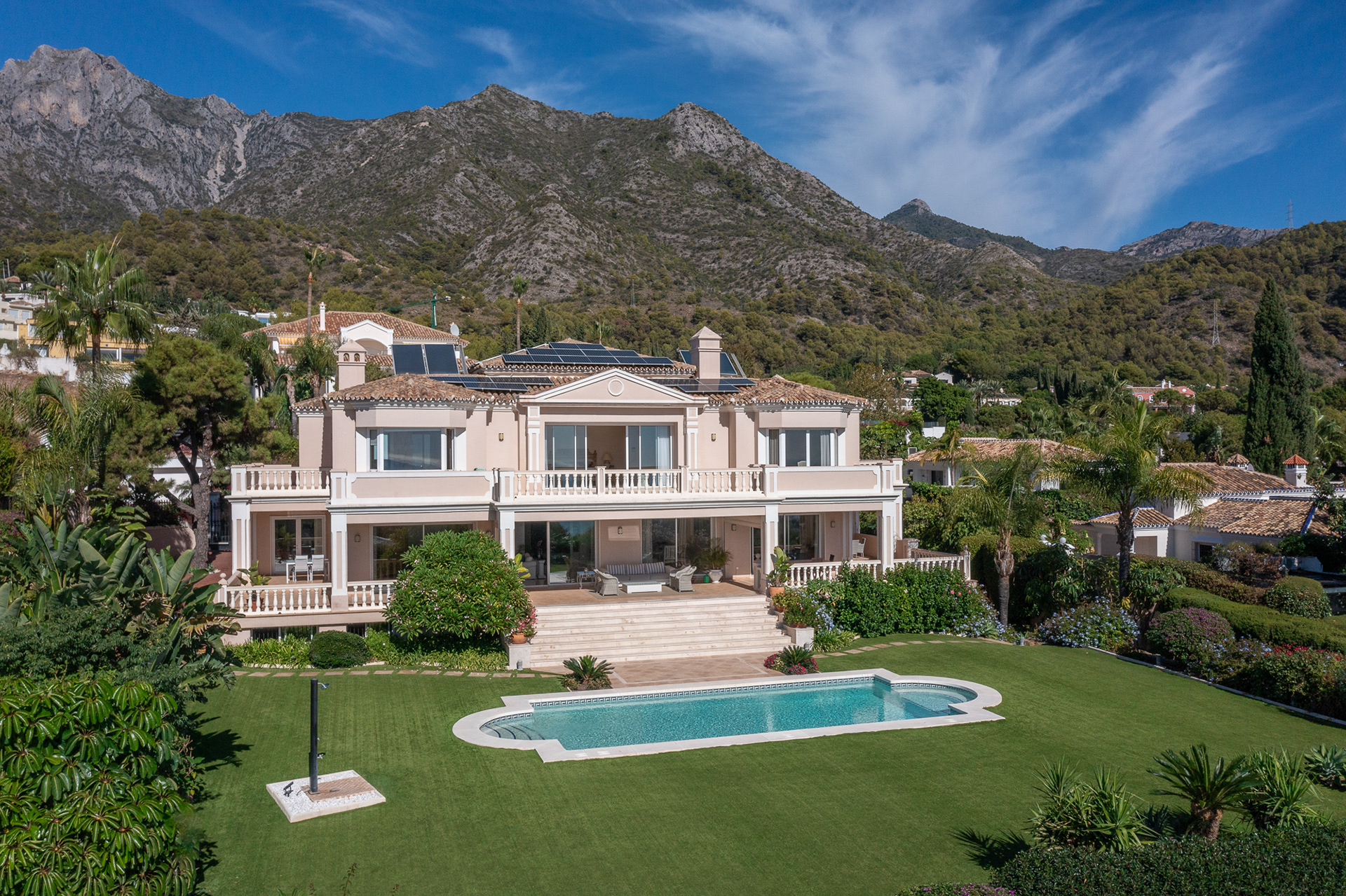High-end real estate image production featuring a luxury Marbella villa with drone photography, mountain backdrop, landscaped gardens, and private pool.