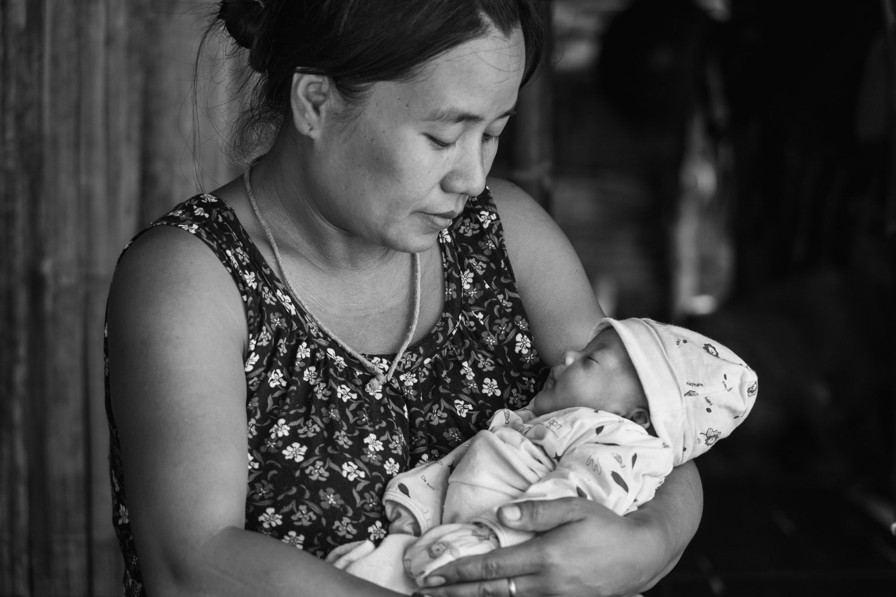 Karen displaced mother and her newborn child in a camp near the Thai border in territory controlled by the Karen National Liberation Army (KNLA). They have fled their village after repeated air attacks by the Myanmar military. Widwspread terror and attacks against civilians and ethnic minorities have substantially increased since the military coup in 2021, provocing large numbers of displaced persons and refugees. Kanele IDP camp, Way Lay, Kayin State, Myanmar. June 2022
