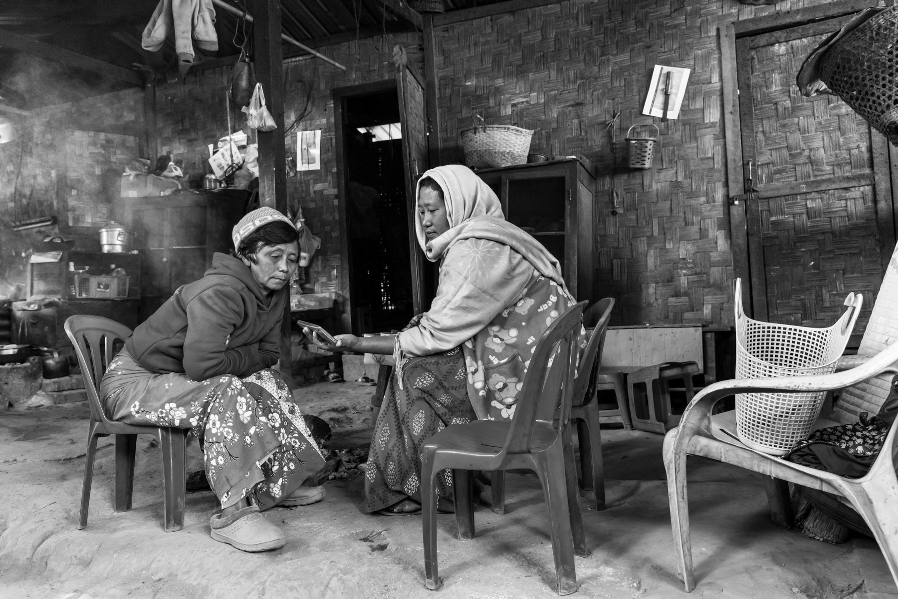 Kachin women sharing a cell phone in their temporary shelter in a camp for internally displaced persons. There are more than 130 IDP camps througout Kachin State hosting more than 100,000 displaced persons. KBC IDP camp in Momauk, Myanmar, January 2020