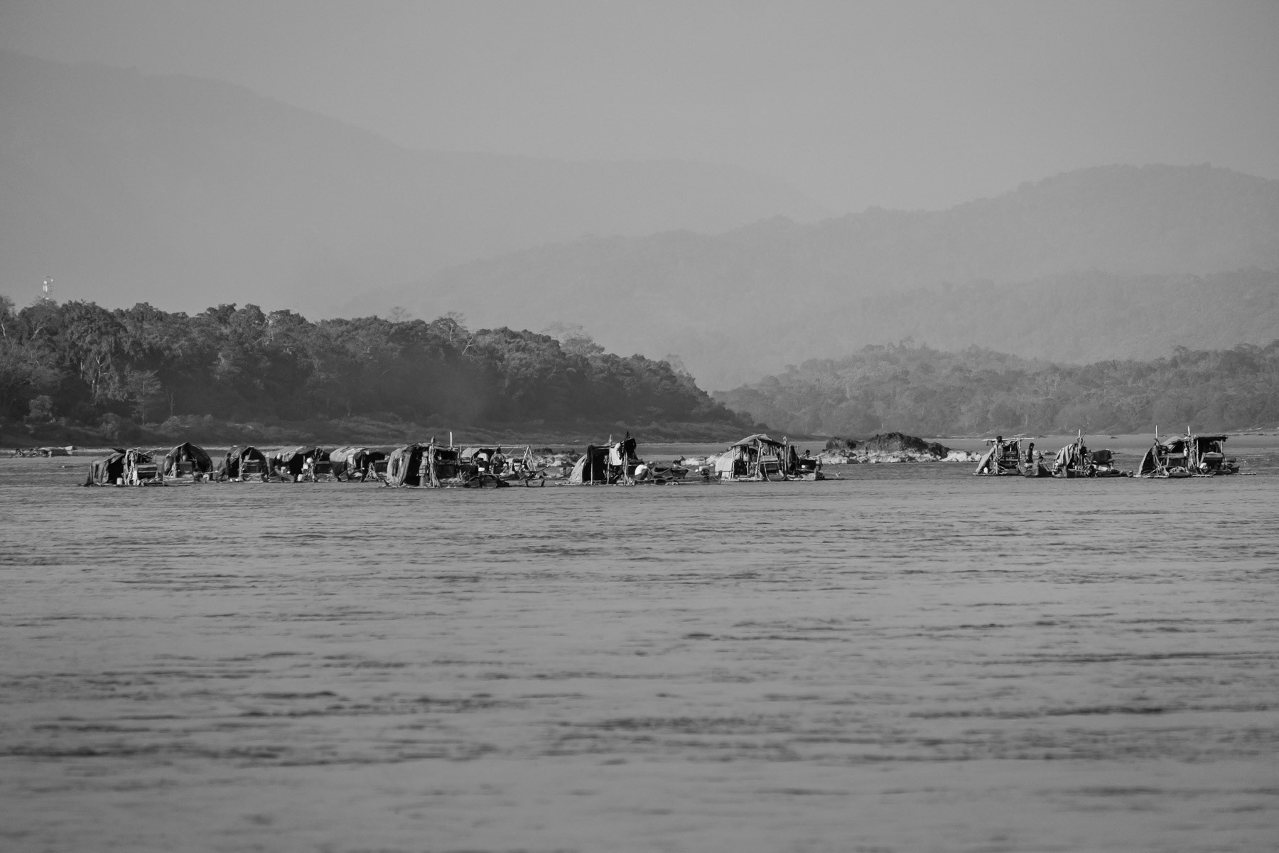 Rafts used by local small scale gold divers. The season lasts from December to the end of March. One boat makes in average 60 to 80 USD per day and consists of 2 divers who dive 3-4 hours each, one in the morning and the other in the afternoon while the other stays on the raft. They dive at a depth of 10 to 15m with compressed air. Their equipment is extremely rudimentary and accidents occur frequently. They dive every single day in extremely strong currents and very cold water not exceeding 10-12C. With a large diametre hose they suck soil and sediments from the river bed up to the boat. Mercury, which is very toxic, is being used to make the gold stand out and blink. All the operations are done on the boat. Only people from the nearby villages are allowed to operate small scale gold digging activities, most of them are from the Lazi Kachin minority. Irrawaddy river north of Myitkyina, Kachin State, Myanmar, February 2020