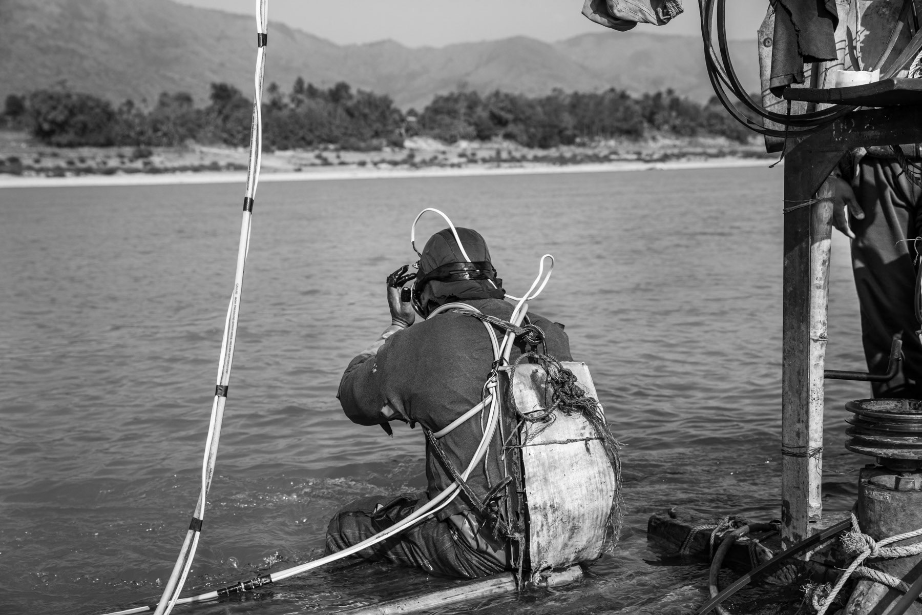 A gold diver getting ready to spend 3-4 hours underwater sucking up soil and sediment from the riverbed through a large hose. A team of 2 divers make in average 60 to 80 USD per day during the gold diving season between December and March. Irrawaddy River, Kachin State, Myanmar, February 2020