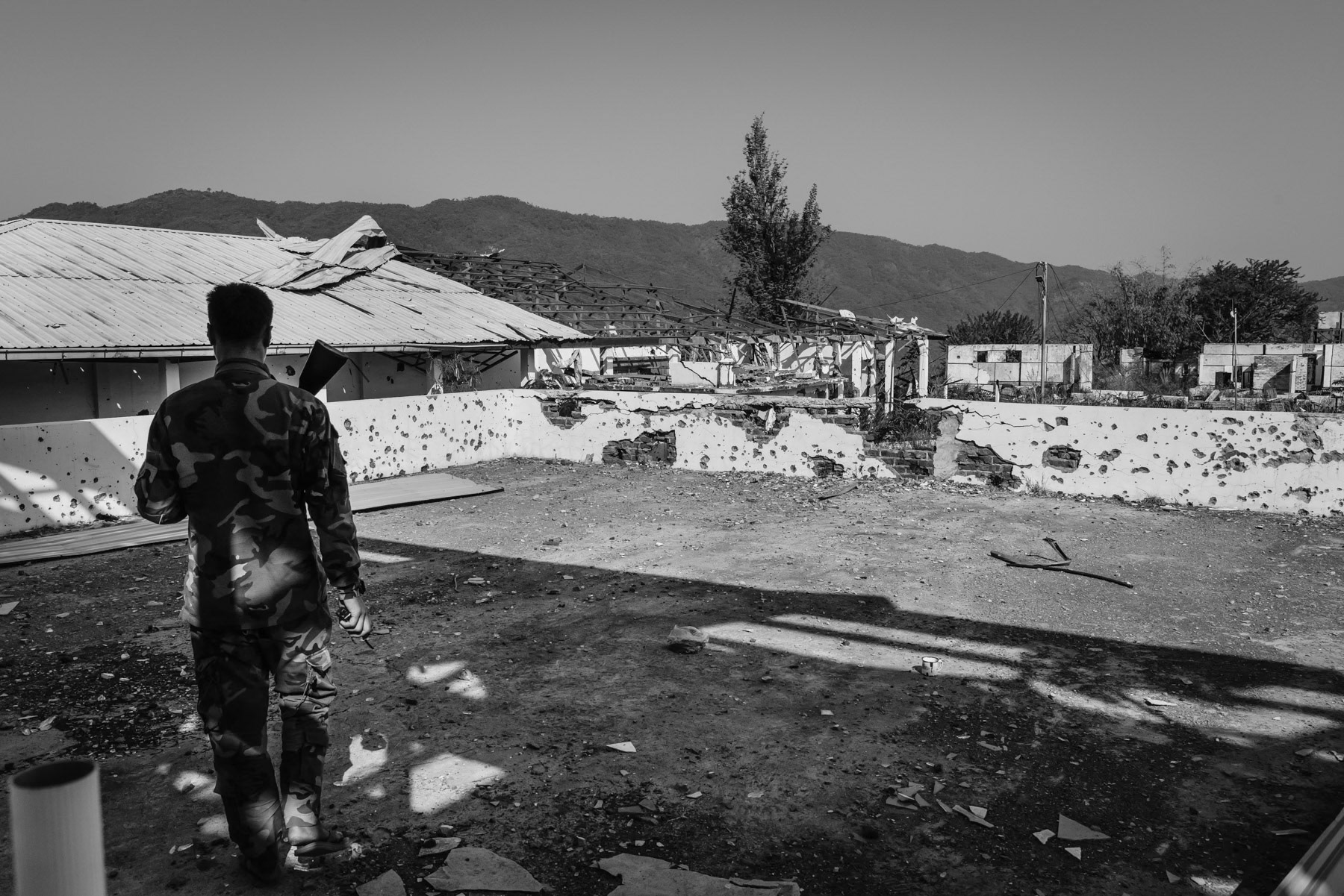 Thantlang, a town of 12,000 before the war is now completely evacuated of its civilian population. The town has been completely destroyed and mostly burned to the ground. Until this day the town is divided between a Myanmar military conrolled part and the other half controlled by the Chin Defense Forces (CDF). Merely a couple of hundred meters separates them downtown. Some of the most violent and intensive combats in Chin State are taking place to this date in Thantlang. CDF positions in a hospital buiding on the frontline. Thantlang downtown, Chin State, Myanmar, April 2024
