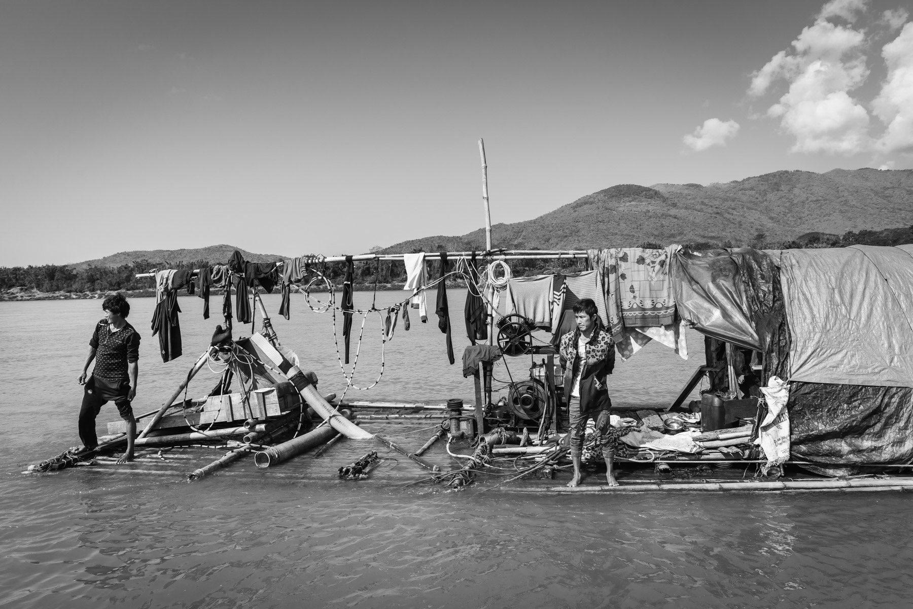 Divers on a small scale gold digging raft. Divers dive up to 2 hours at 15 metres depth and up to 2 times per day for about 4 months per year. This health hazardeous activity generates very little income as the large industrial gold digging companies upstream extract the bulk of the gold. Divers are regularly confronted with decompression sickness due to repetitive diving and mercury poisoning. Irrawaddy river north of Myitkyina, Kachin State, Myanmar, March 2019