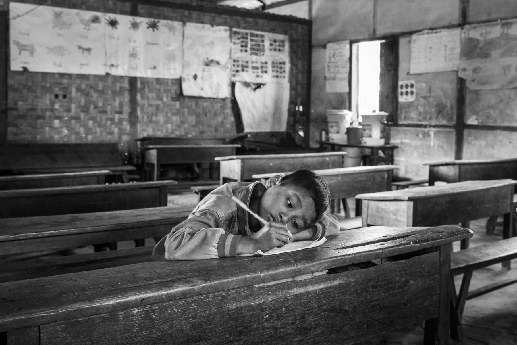 A Kachin boy in the classroom. Robert IDP Camp hosting 4000 internally displaced persons (IDP) of the Christian Kachin Minority. Over 100,000 Kachin are still displaced within Kachin State since the armed conflict resumed in 2011 between the Myanmar military and the Kachin Independence Army (KIA). Bhamo township in government controlled territory Myanmar, January 2020