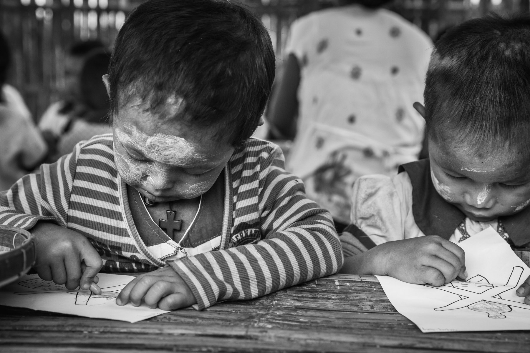 Small children at the kindergarden colouring the sign of plastic bottles harmful for the environment. St-Joseph IDP camp, Kachin State, Myanmar, September 2019