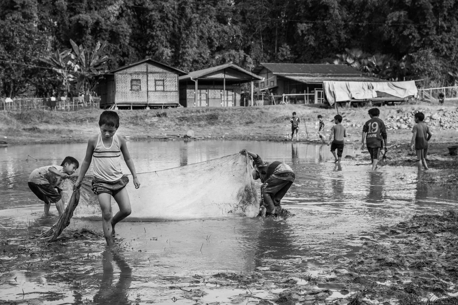 Children fishing in the pond in Puta-o IDP camp where 300 people live since being displaced from their villages in the mountains in 2011 when fighting broke out between the Myanmar Army and the Kachin Independence Army. Puta-o, Kachin State, Myanmar, February 2020