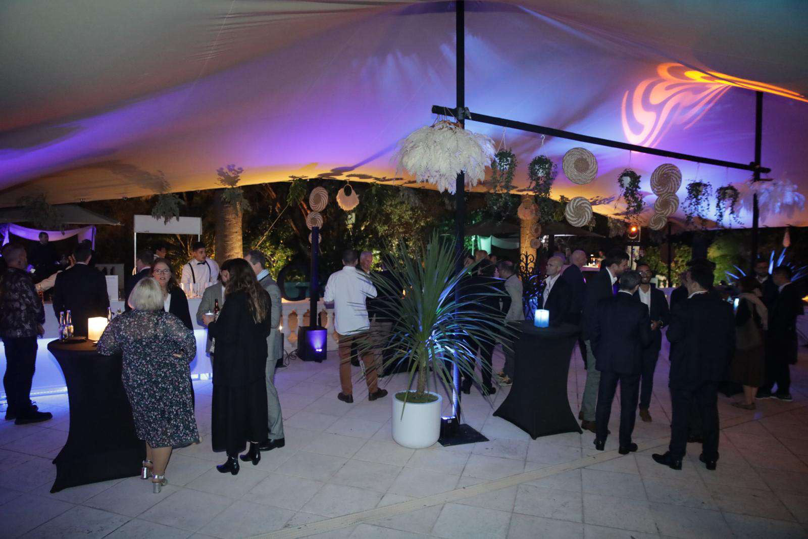 Crowded luxury reception under a large marquee for a corporate event.