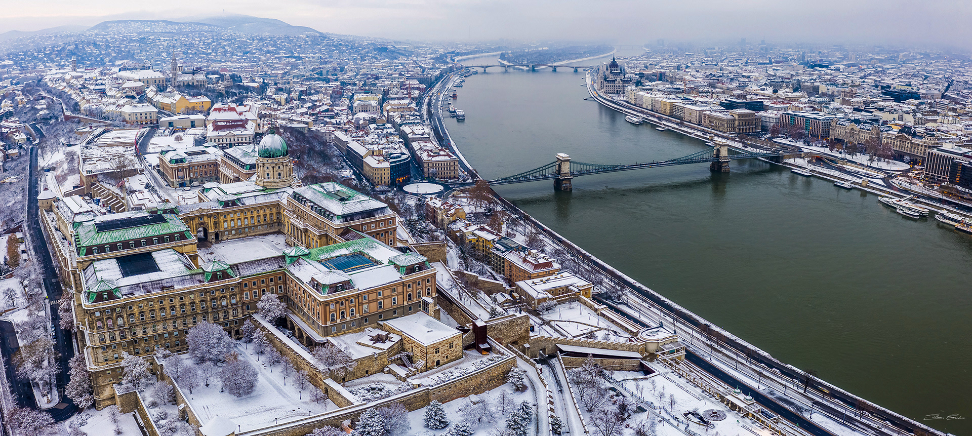 Aerial panoramic view of snowy Buda Castle and Széchenyi Chain Bridge