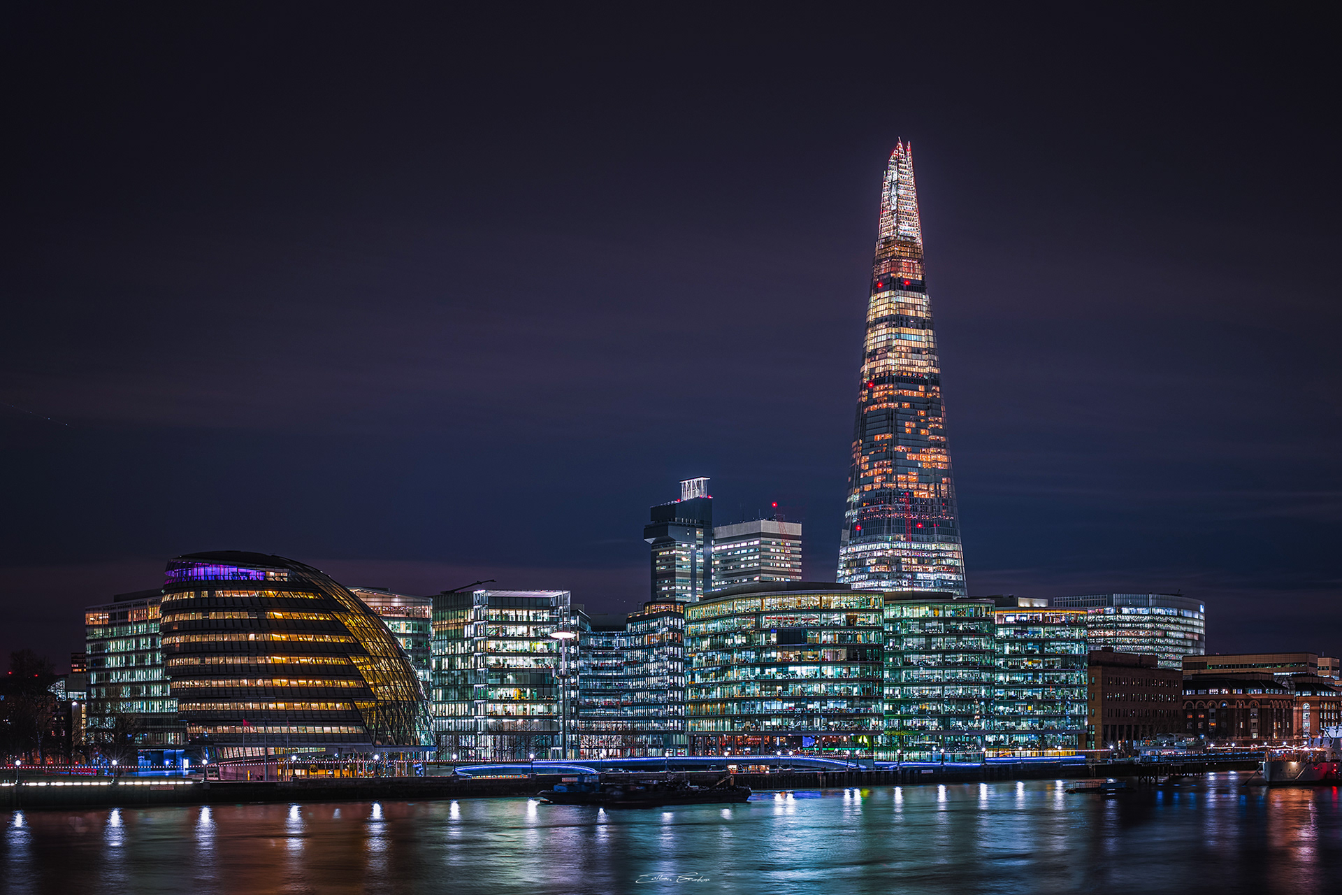 Riverbank of London with City Hall building and The Shard by night