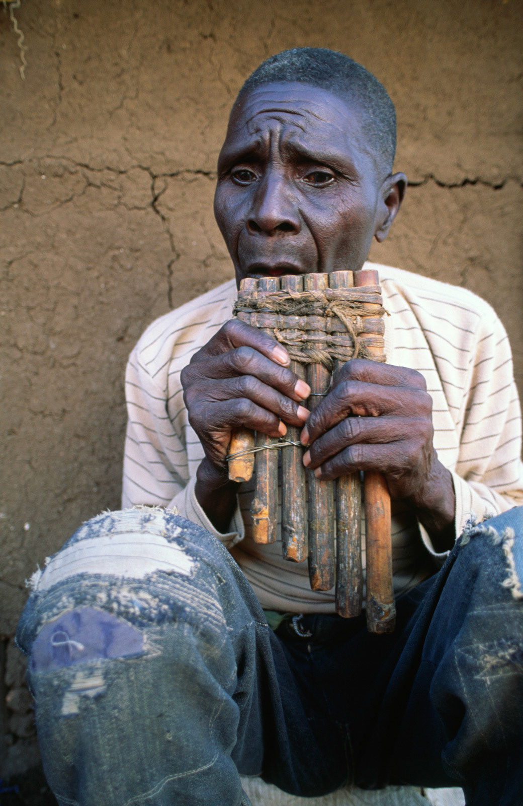 Old man playing bamboo pipes. Zimbabwe