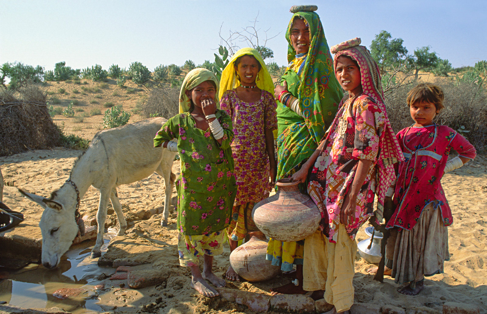 Mother and daughters at village well. Thar Desert, Pakistan