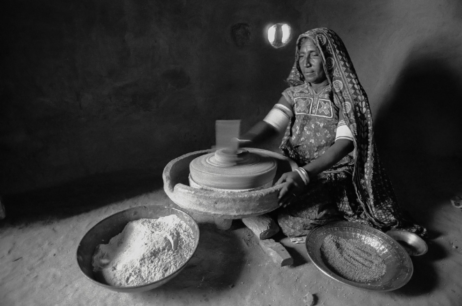 Grinding corn between two stones (chakki) in Gujarat, India