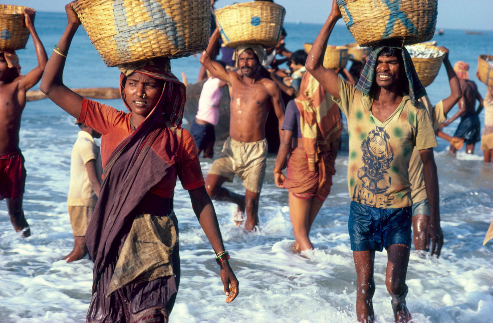 Villager porters carrying fish ashore. Kerala, South India