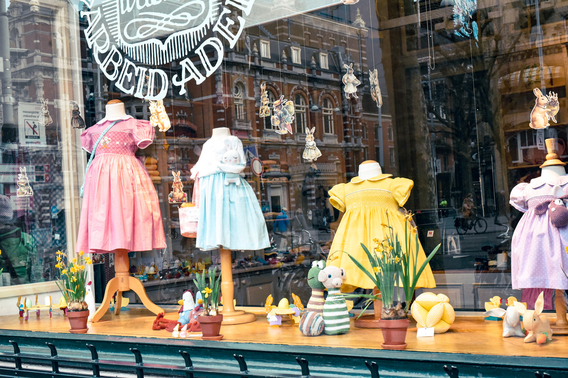Spring smocked dresses in a store window in Amsterdam, theatre building in reflection