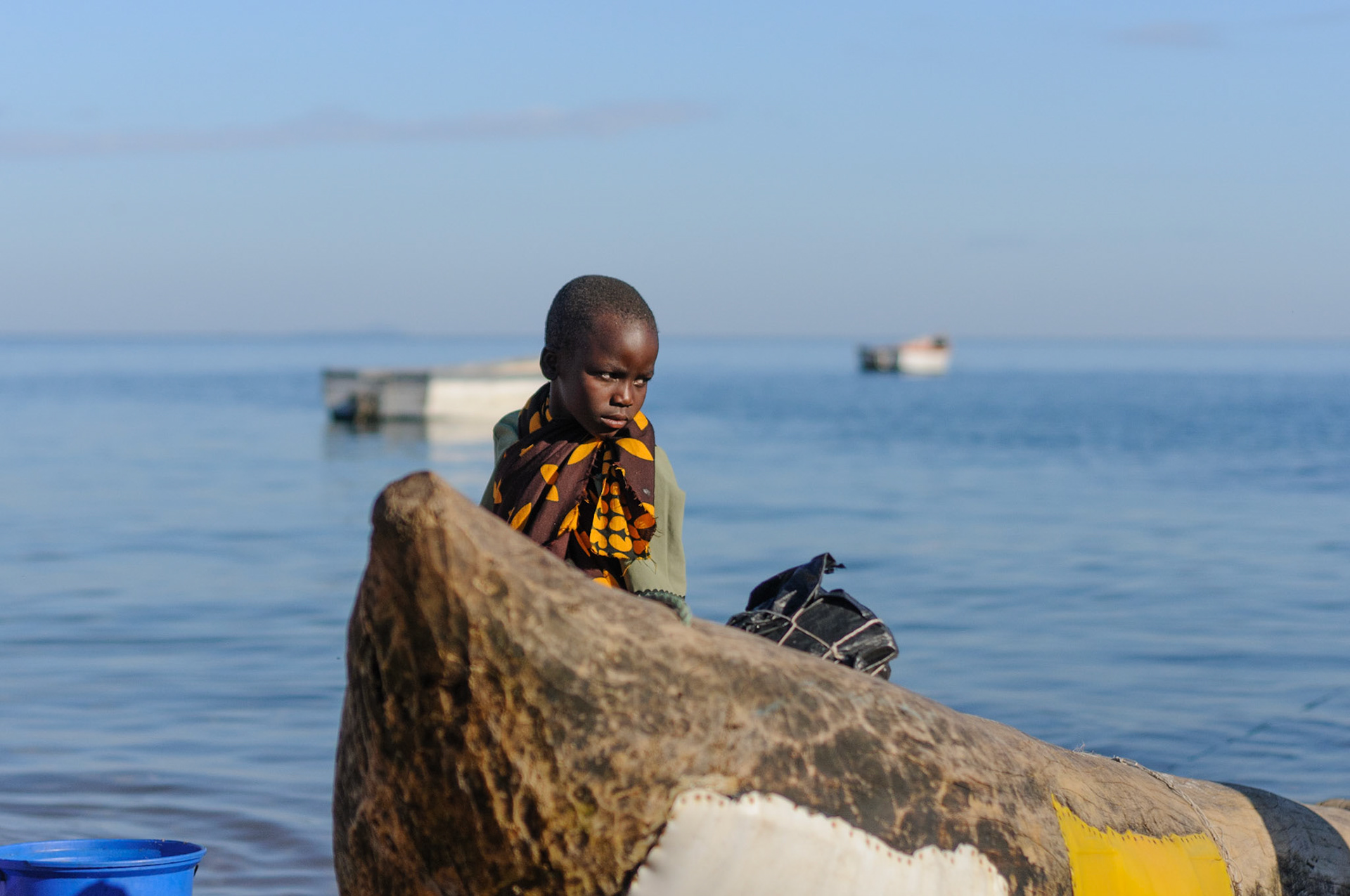 Boy standing next to wooden dugout canoe, Lake Malawi