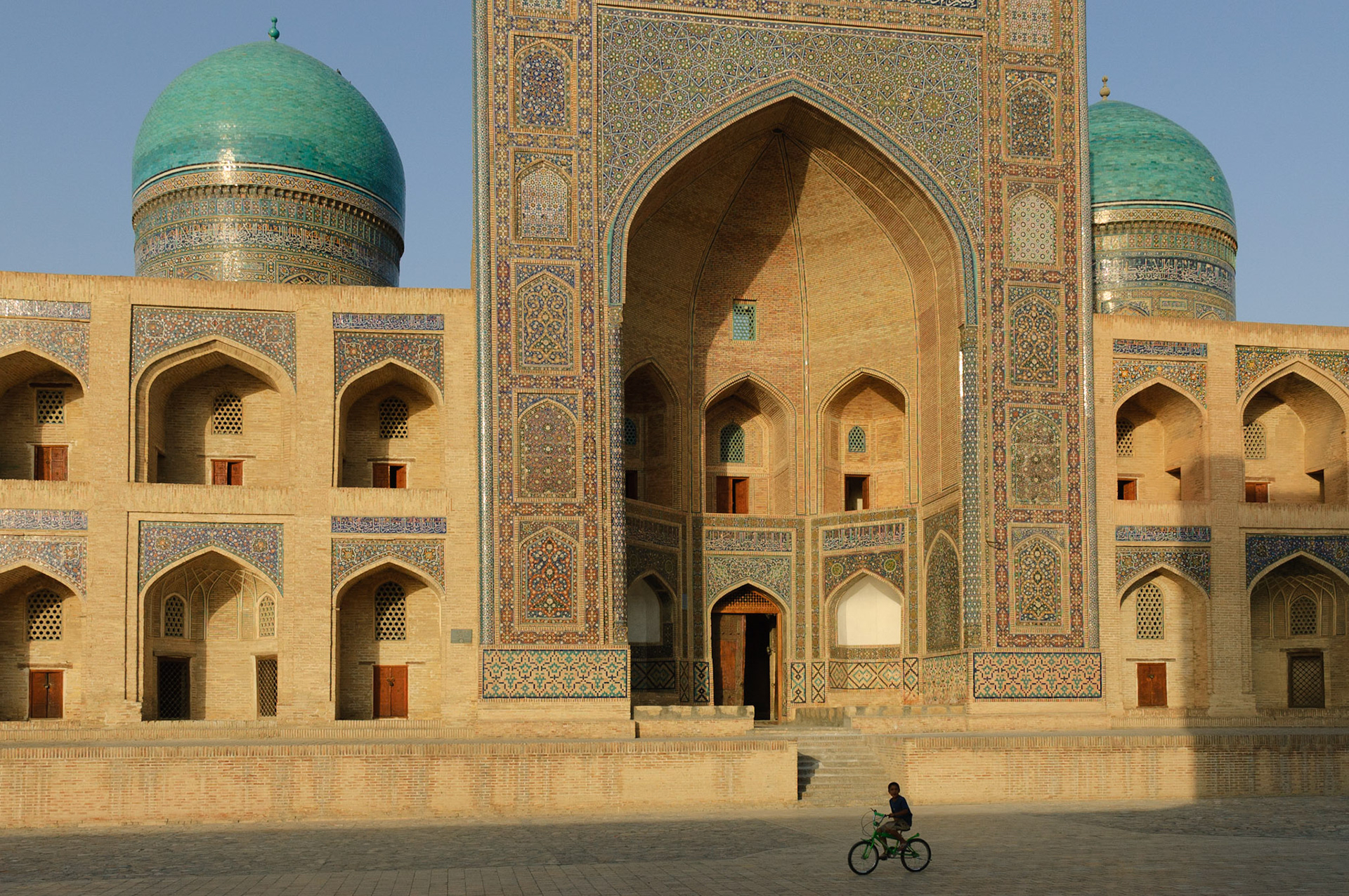 boy cycling in front of Mir-i-Arab Medressa, Bukhara