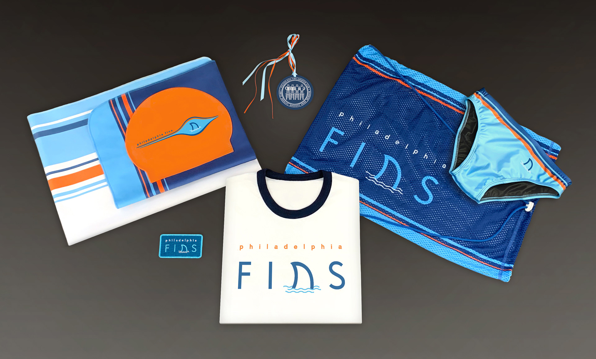 Philadelphia Fins gear: microfiber towels, swim cap, iron-on patch, ringer tee, award, mesh bag, euro brief