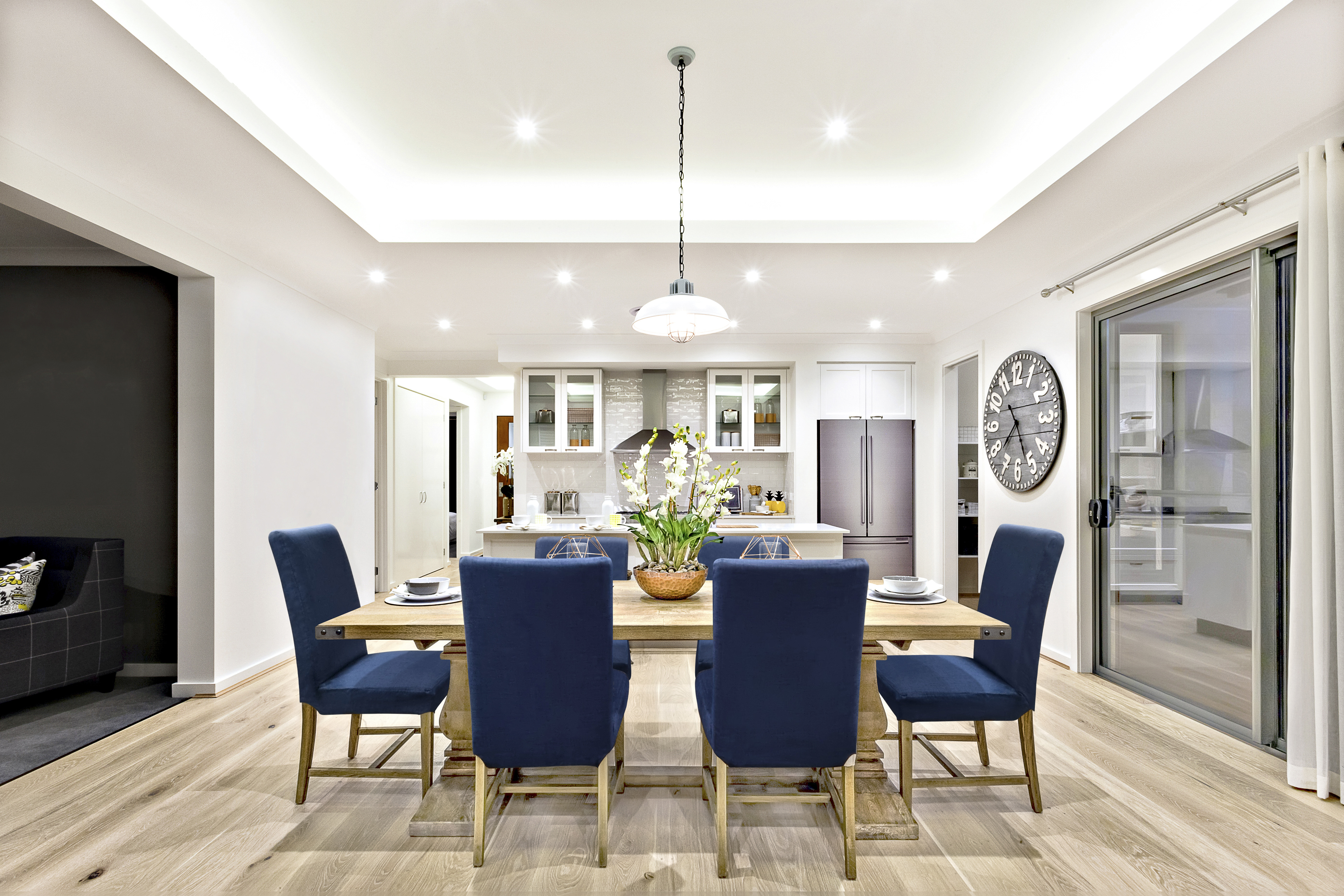 Modern kitchen interior in white colors with dark blue chairs and wooden floor.