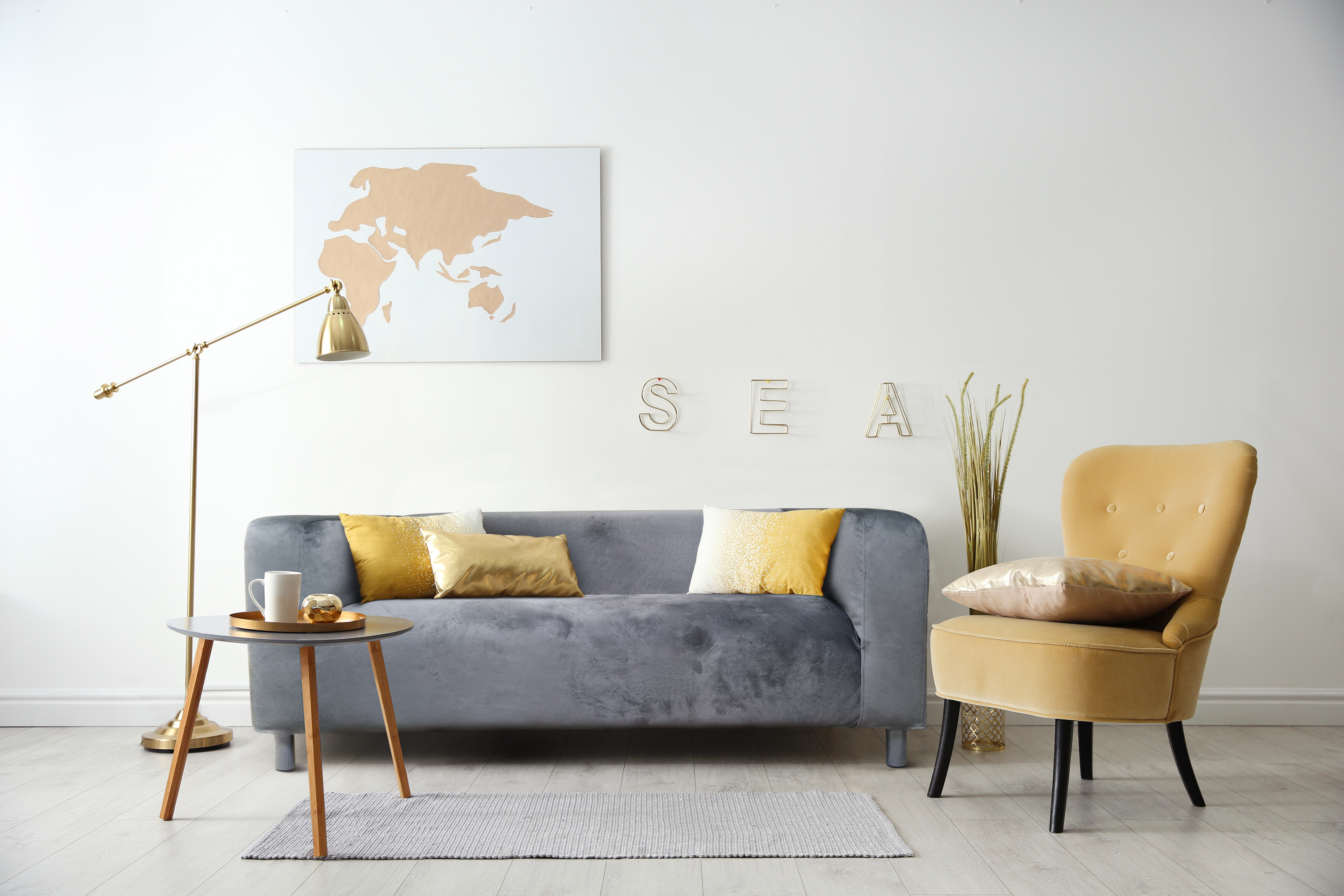 Modern living room with grey velvet sofa in white colors with beige accents.