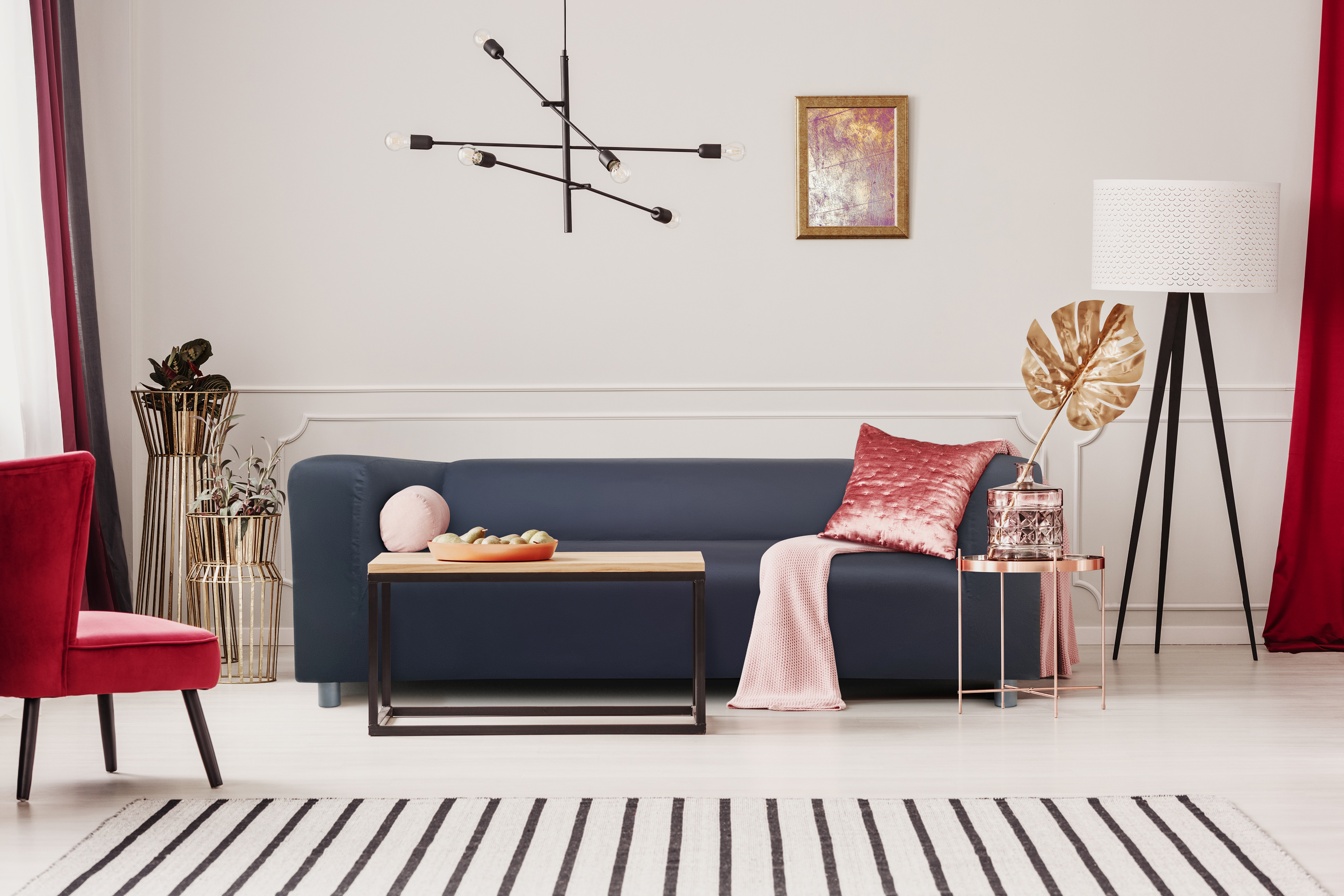 Modern living room with dark blue sofa in cream colors with red, golden and black accents.