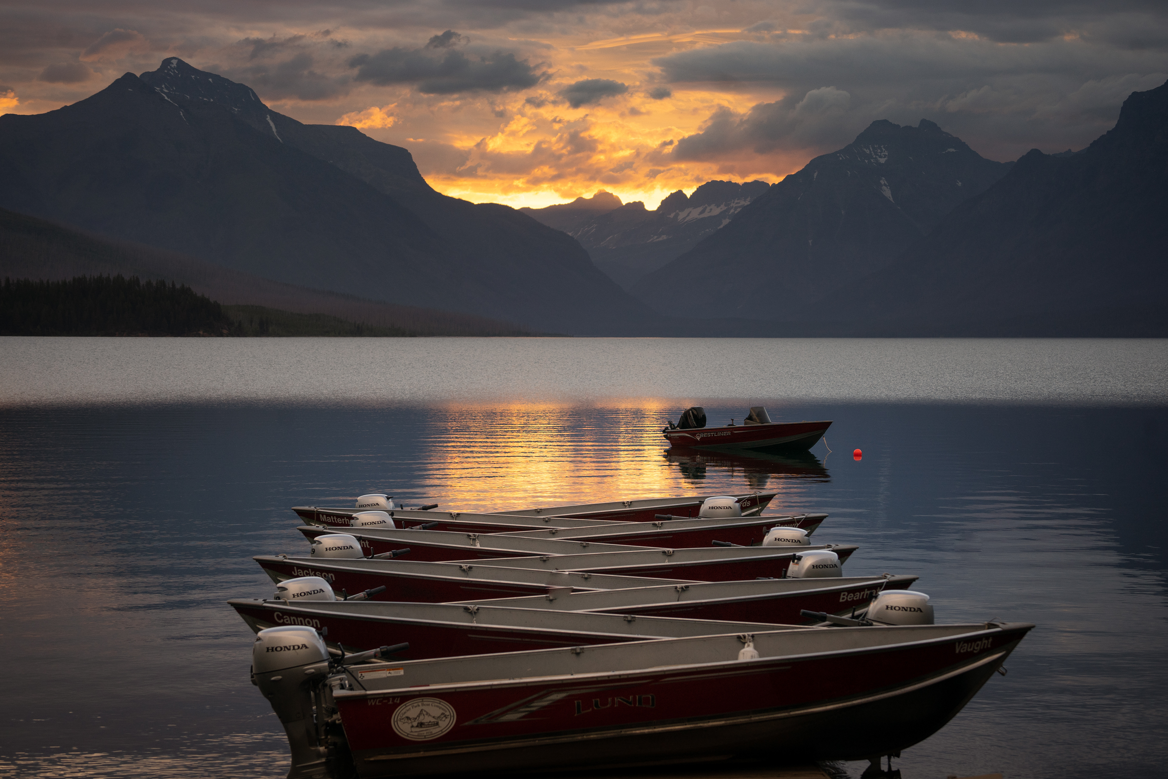 A firery glow illuminates the sky at the far end of Lake McDonald. Glacier National Park