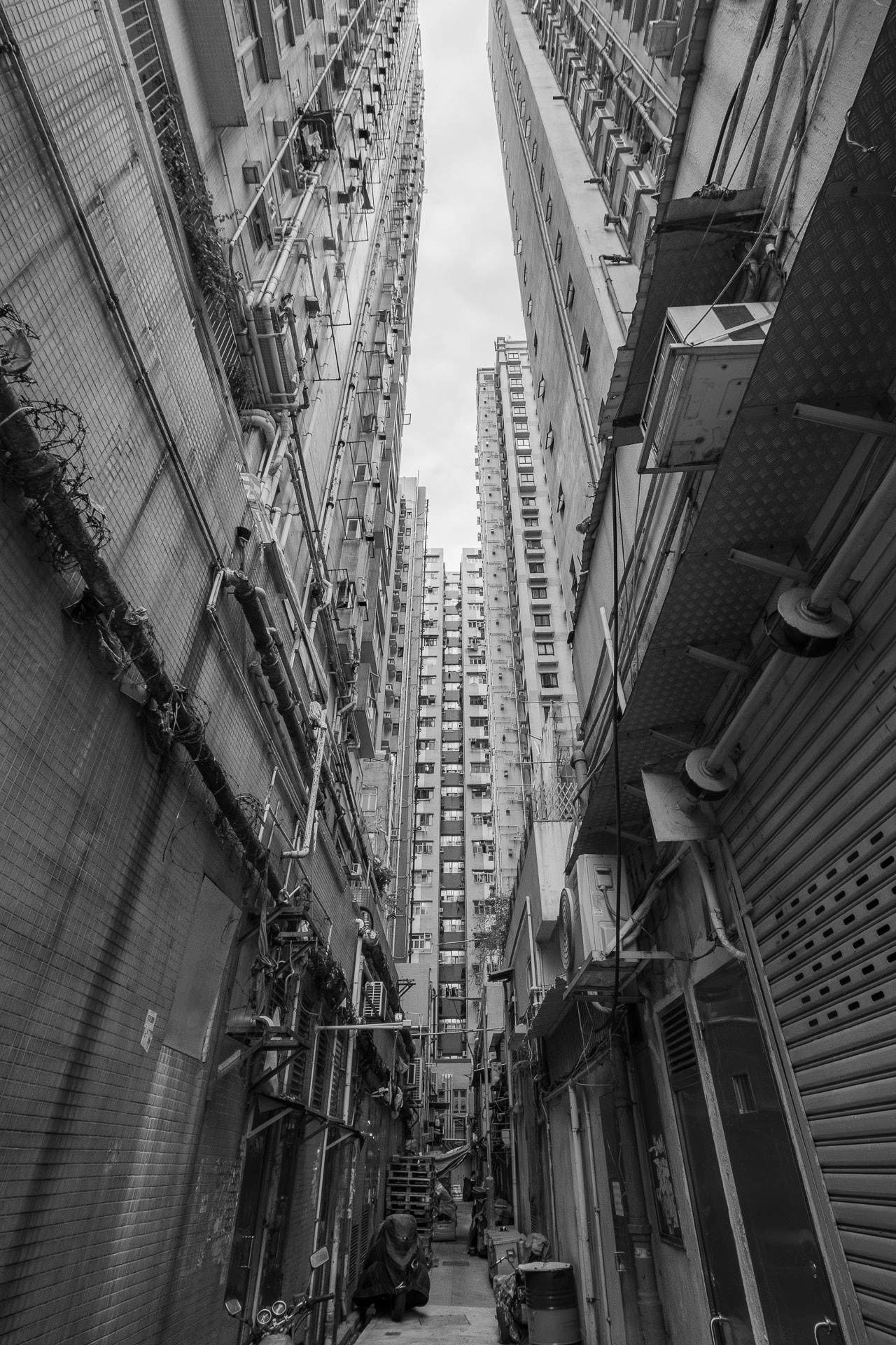 Back alley with pedestrians in Tai Kok Tsui, Hong Kong during the day (black and white photography)
