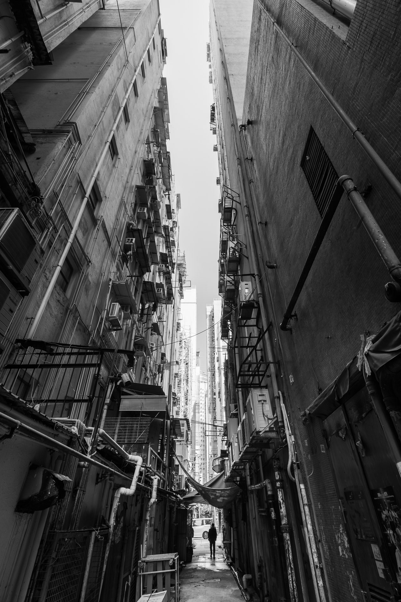 Back alley with pedestrians in Yau Ma Tei, Hong Kong during the day (black and white photography)