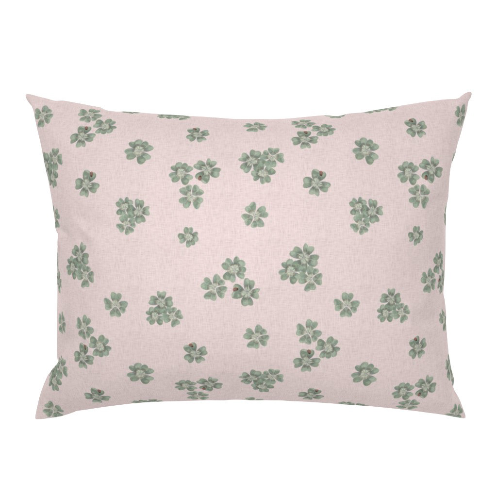 Square cushion cover in Clover Scatter blush pink colourway with sage green clover motifs, on a white background