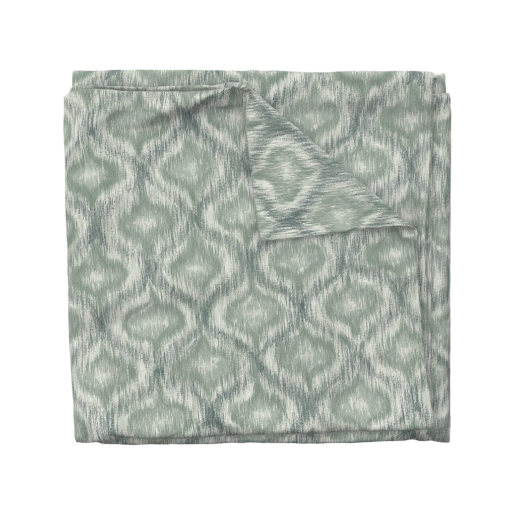 Folded fabric swatch of Boho Style Ikat Ogee in dusty teal, showing the allover ogee repeat pattern, by Lemon Dessin