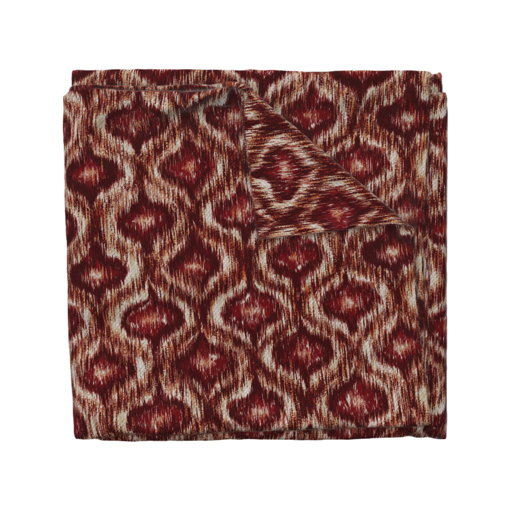 Folded fabric swatch of Boho Style Ikat Ogee in rust red, showing the allover ogee repeat pattern, by Lemon Dessin