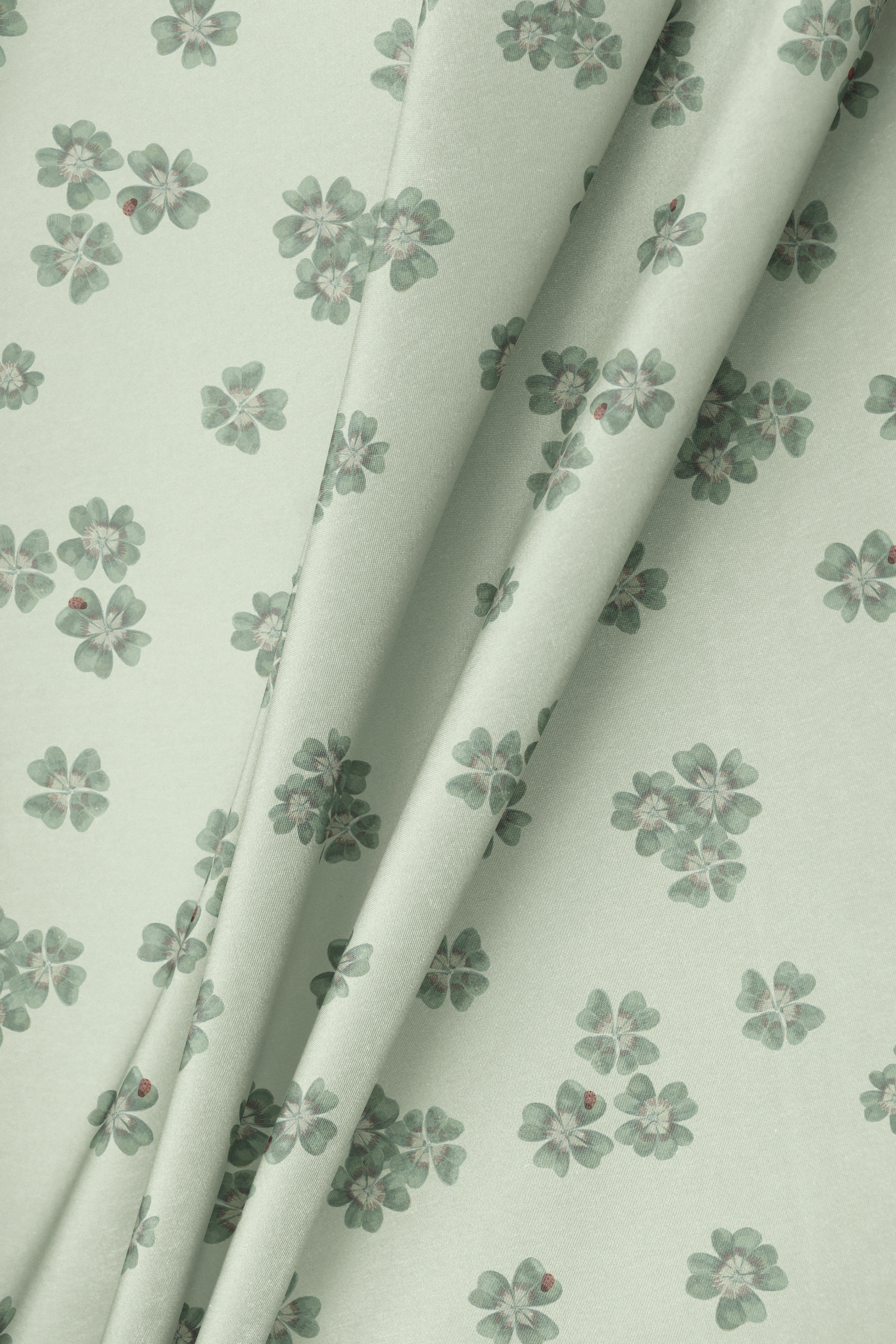 Draped fabric in Clover Scatter sage green colourway showing pattern repeat and drape on a light background