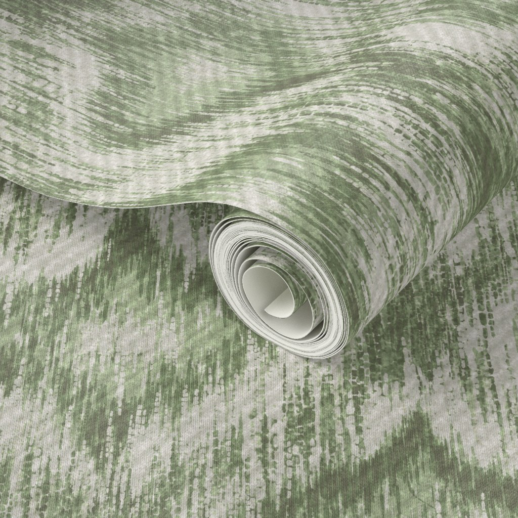 Rolled wallpaper in soft sage green ikat ogee pattern, showing the muted earthy colourway and diffused organic edges of the hand-painted repeat