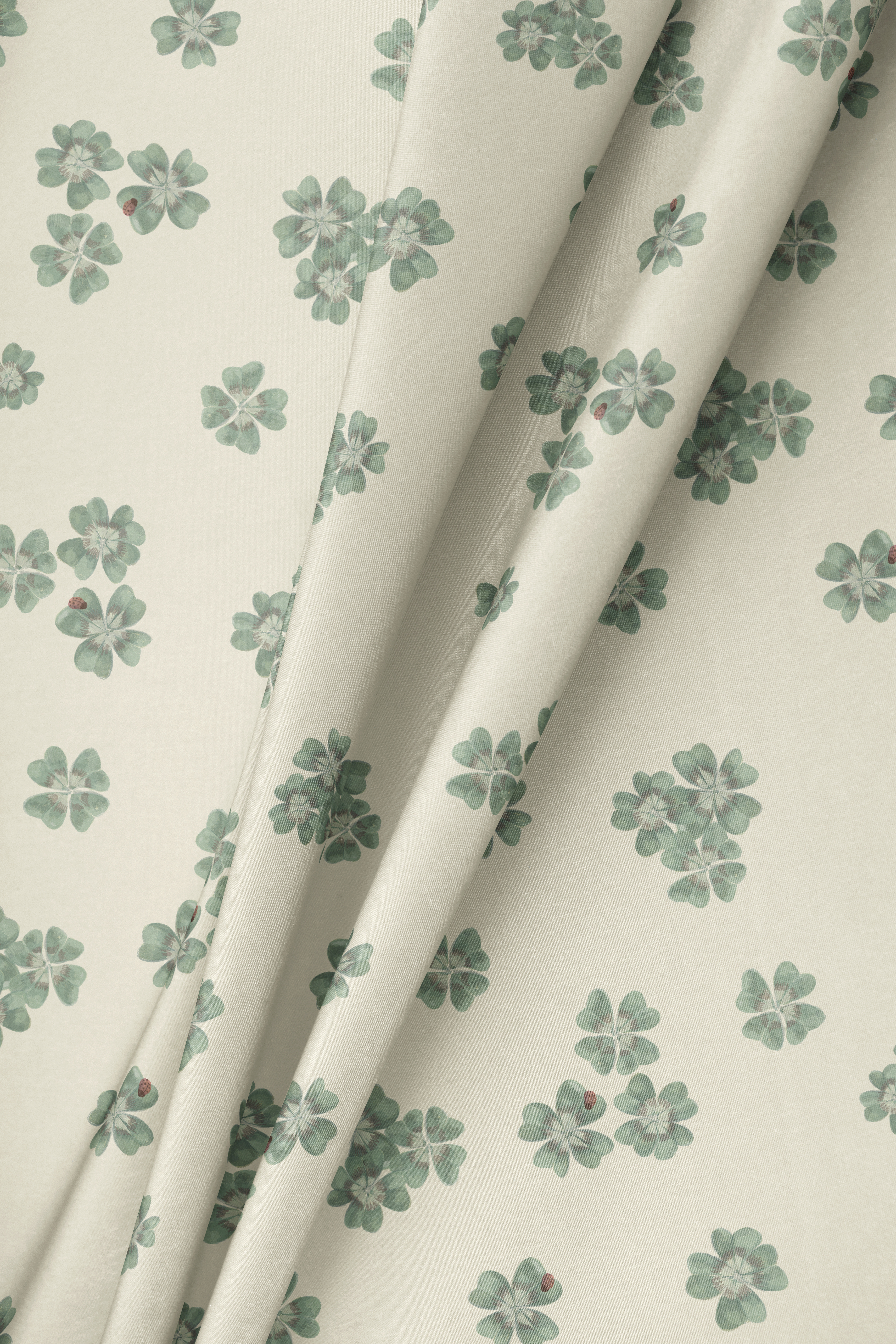 Draped fabric in Clover Scatter cream colourway showing movement and drape, with hand-painted sage green clover scatter pattern