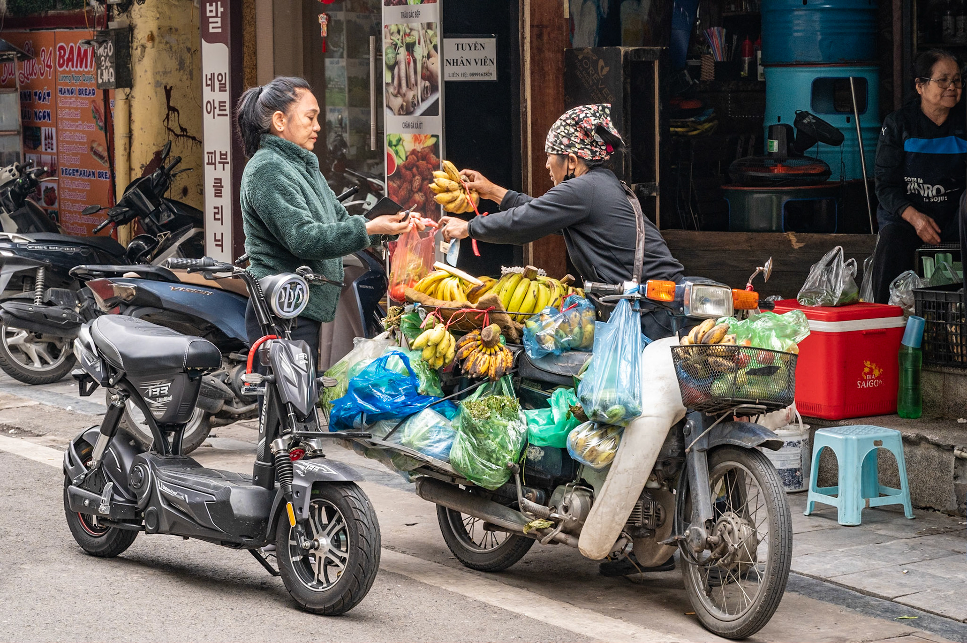 Je suis dans les rues d'Hanoï, la capitale du Vietnam. Ici, il est impossible d'ignorer l'omniprésence de la mobylette ou des motos, car les deux roues font office de voiture familiale, avec les enfants entassés entre les deux parents, de magasin ambulant ou de petits camions .... Sur les sept millions d'habitants d'Hanoï, il est comptabilisé cinq millions de mobylettes ou motos, contre seulement cinq cent mille voitures. Et voir des "bouchons" de mobylettes ou l'imbroglio pétaradant aux carrefours est assez incroyable !