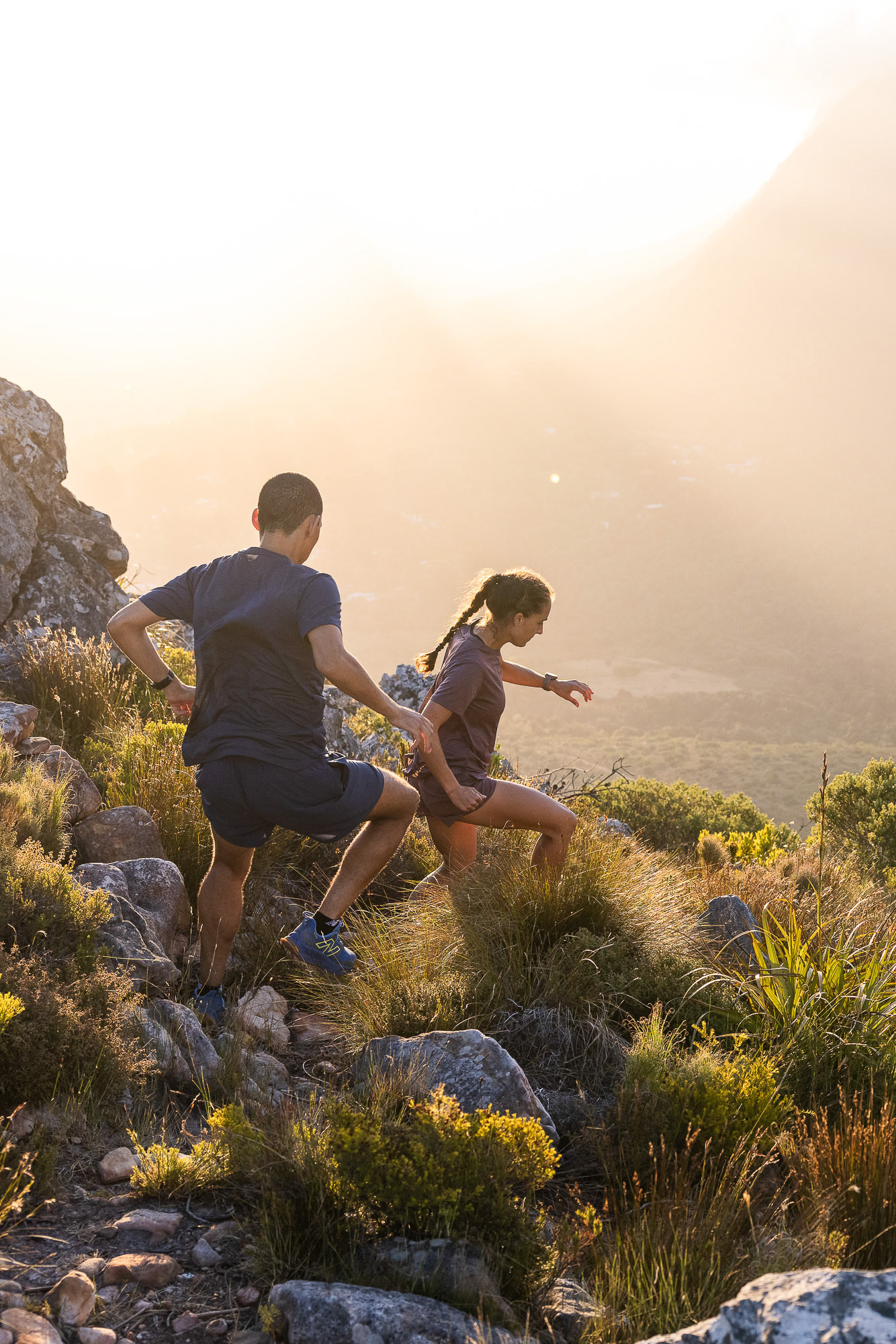 Two trail runners running in Cape Town wearing New Balance Fresh Foam X Hierro V8 trail shoes summating a mountain ledge photographed by Casey Crafford