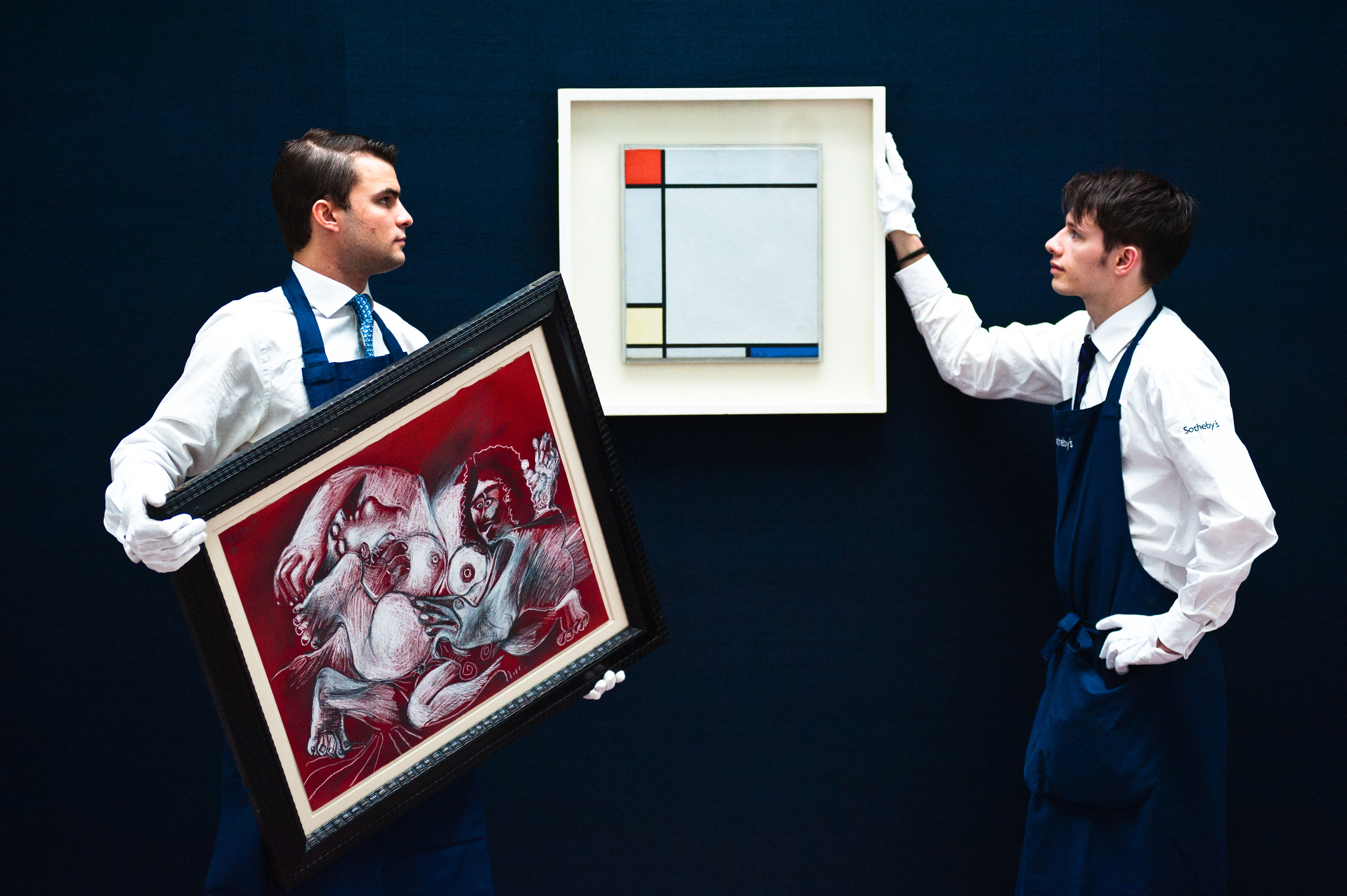 London,UK - 14 June 2013: Sotheby's employees bring a work by Piet Mondrian entitled ?Composition with red, Yellow amd Blue, 1927) (Est. £4.5-6.5 million) (R) and 'Etreinte' by Pablo Picasso (Est. £1.5-2 million) (L) during the preview of this summer auction at Sotheby's. Fotografo a Milano - Photographer Milan