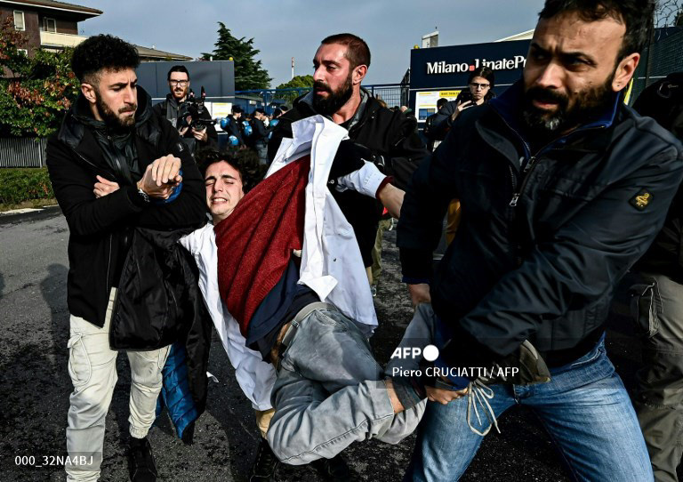 Police officers detain an activist as climate activists from Extinction Rebellion, Scientist Rebellion and Last Generation block the entrance of the "Milano Linate Prime" fixed-base operator (FBO) airport facility in Milan on November 10, 2022, demanding the ban of private jet, tax frequent flyers and introduce taxation of most polluters. (Photo by Piero CRUCIATTI / AFP)